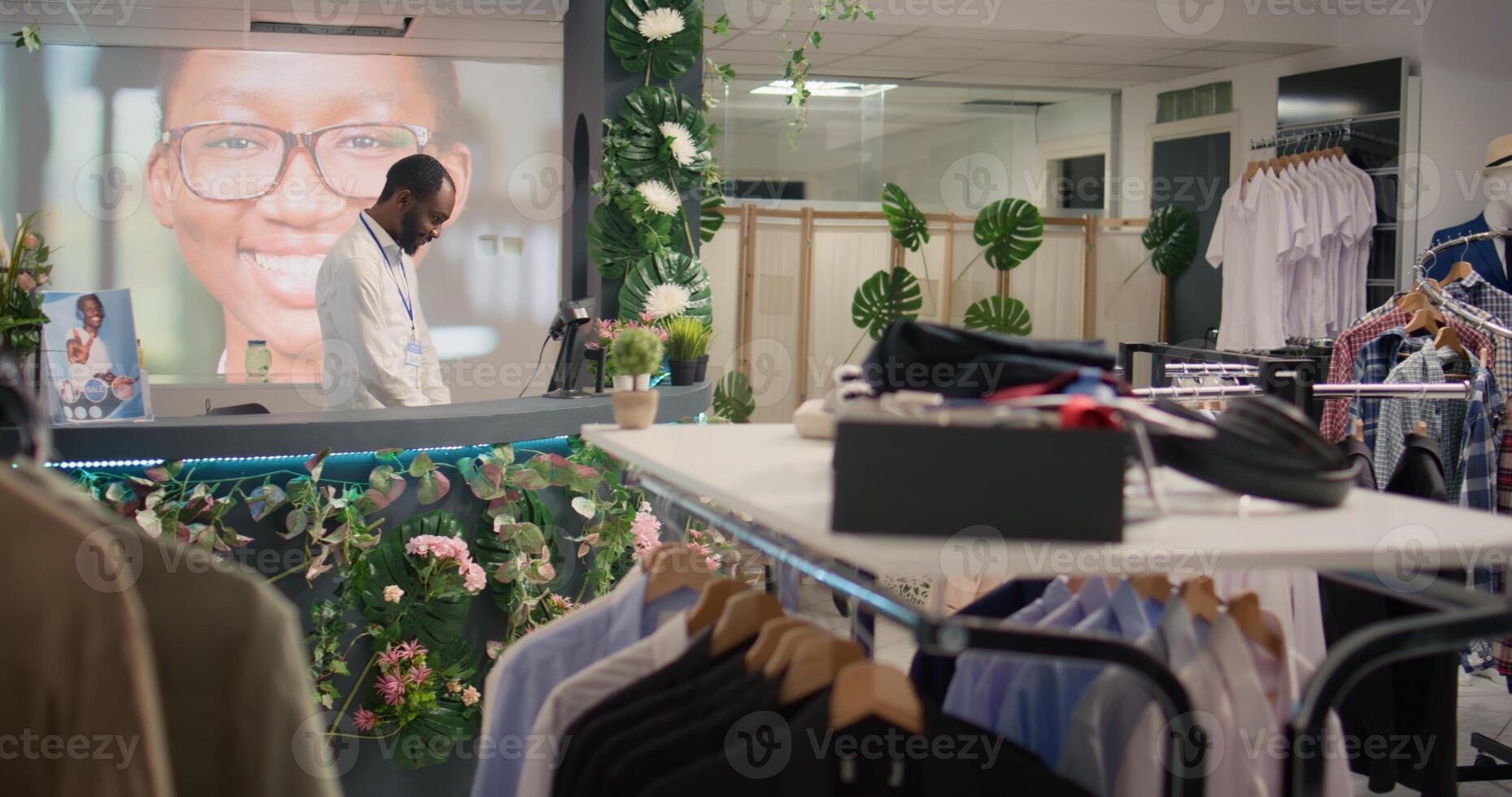 BIPOC man working in luxurious clothing store with elegant assortment of blazers. African american shopkeeper awaiting clients in premium fashion boutique with stylish attire garments photo