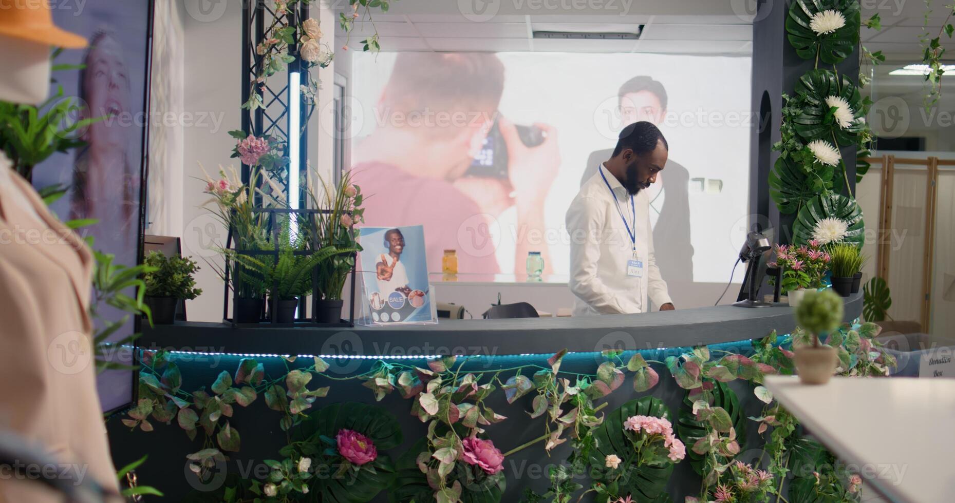 BIPOC retail clerk checking past customers transactions in thrift shop at checkout counter and taking clothes delivery orders. Store manager in empty SH store looking at data on terminal screen photo