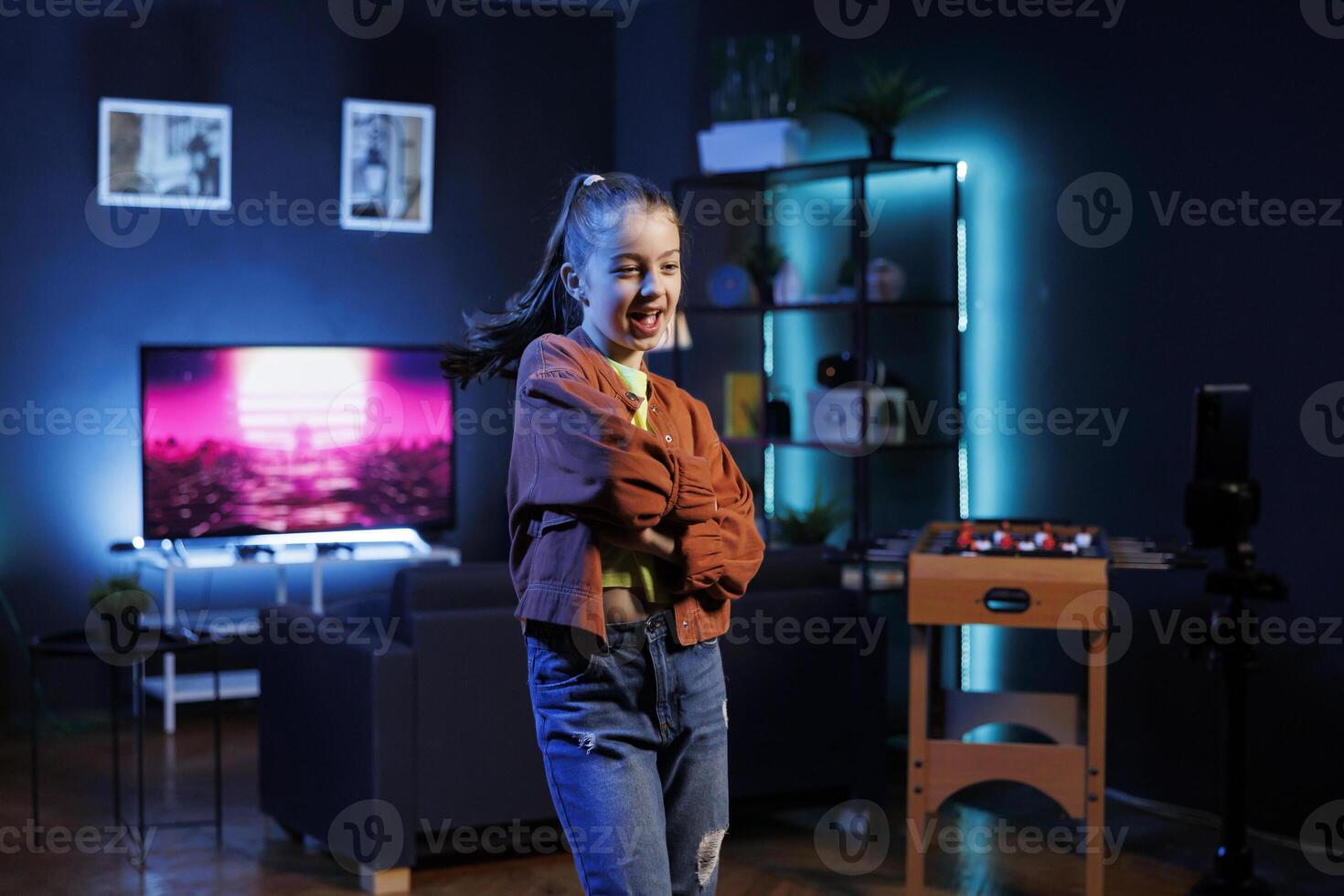 Cute girl filming dance routine on social media networks with cellphone, participating in trending challenge. Gen Z dancer recording video in studio using mobile phone on tripod stabilizer photo