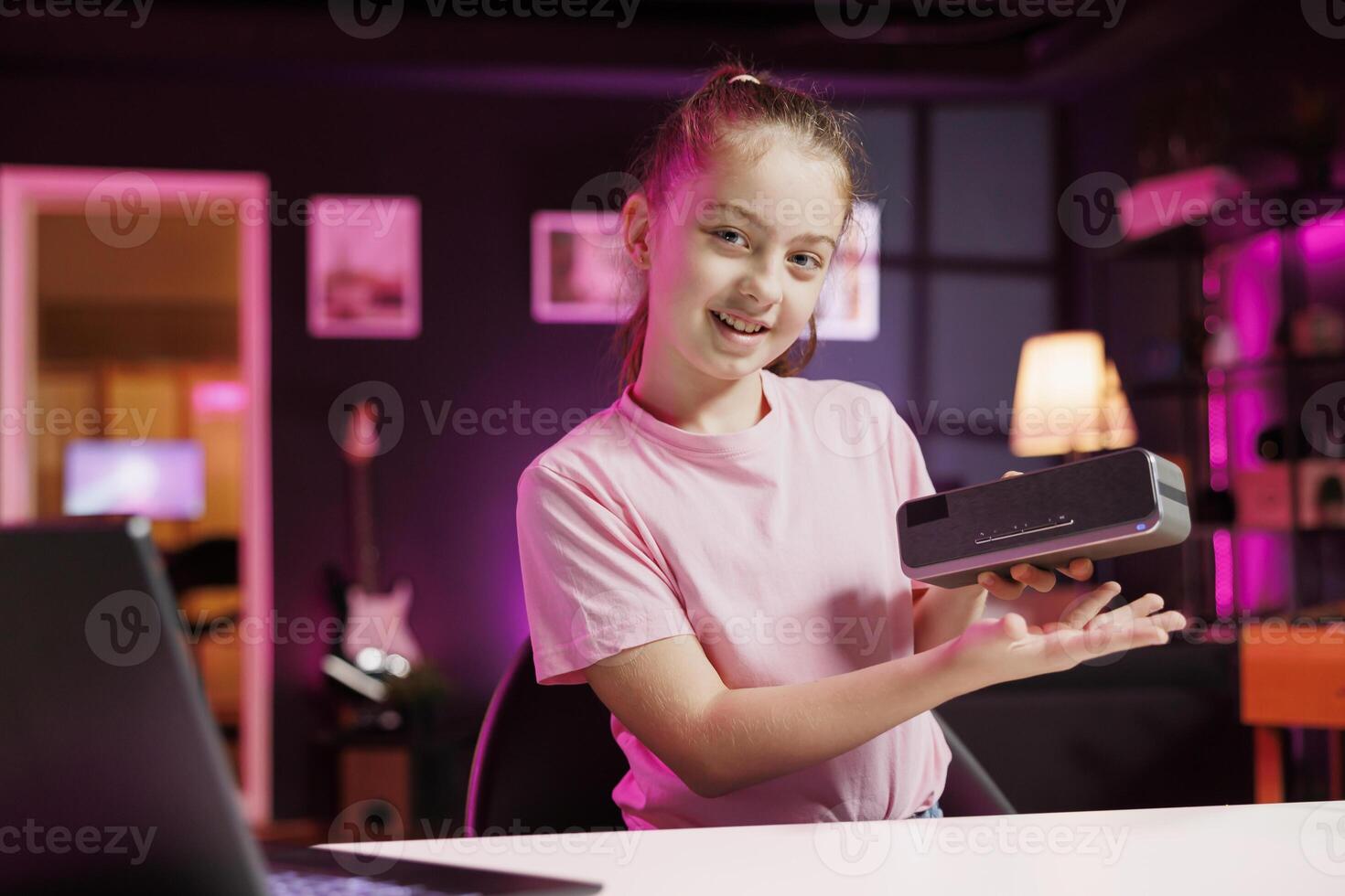Kid influencer sponsored by company producing audio devices to present newly released portable speaker to audience. Child content creator fulfills brand partner contract by advertising musical product photo