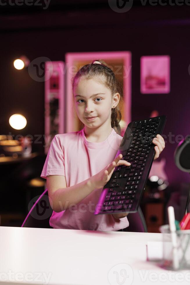 Cute girl showing viewers mechanical keyboard received from sponsoring brand to promote it. Gen Z online content creator advertising wireless gaming computer peripheral from partnering company photo