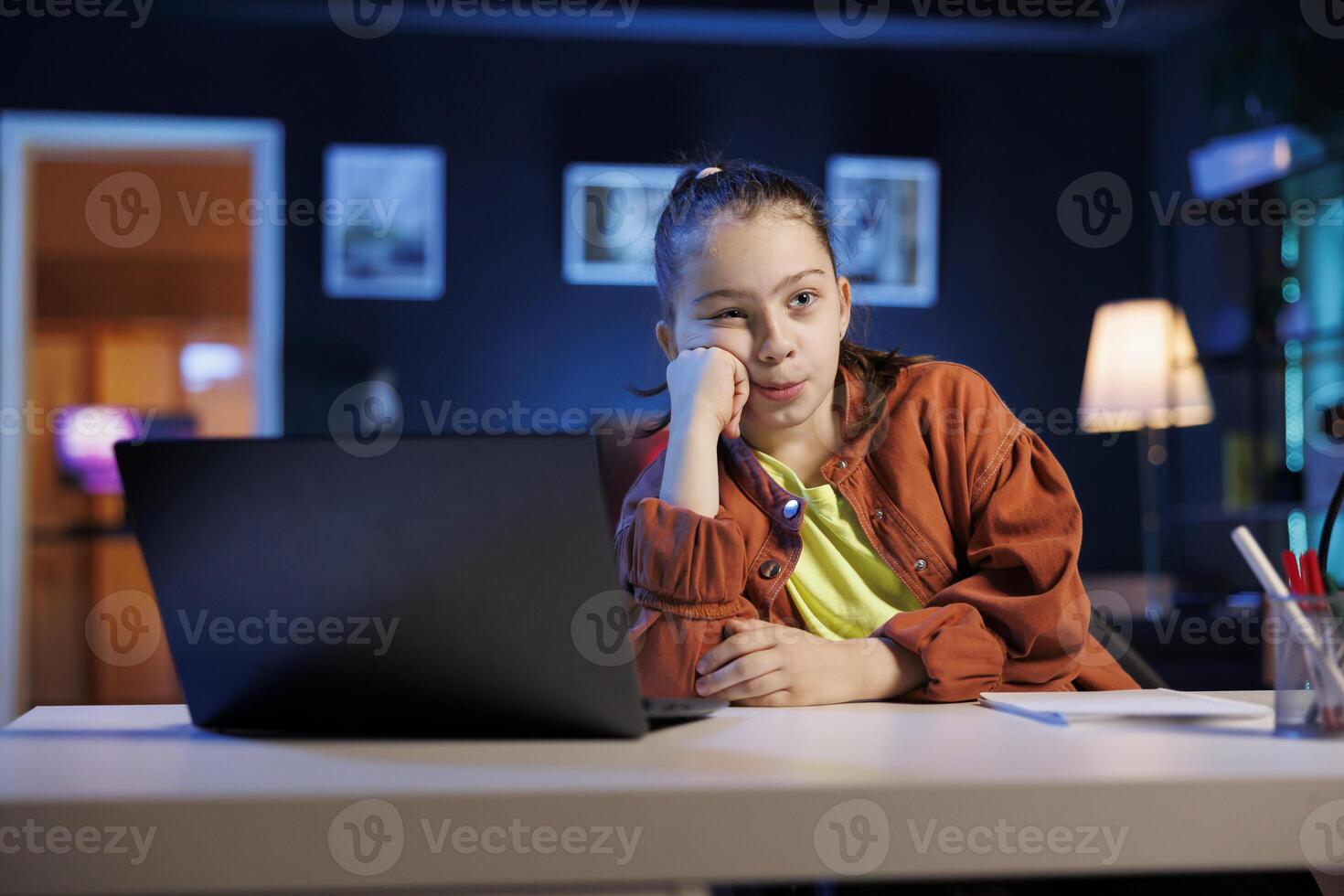 Tired little girl filming with professional gear in living room used as professional studio for recording vlogs. Child captures footage with high tech camera, discussing about boring day at school photo