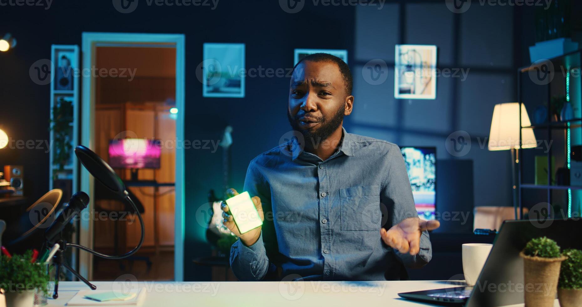African american tech content creator filming technology review of mini RGB lights device illuminating in different colors. Viral internet star showing helpful broadcast production tool to subscribers photo