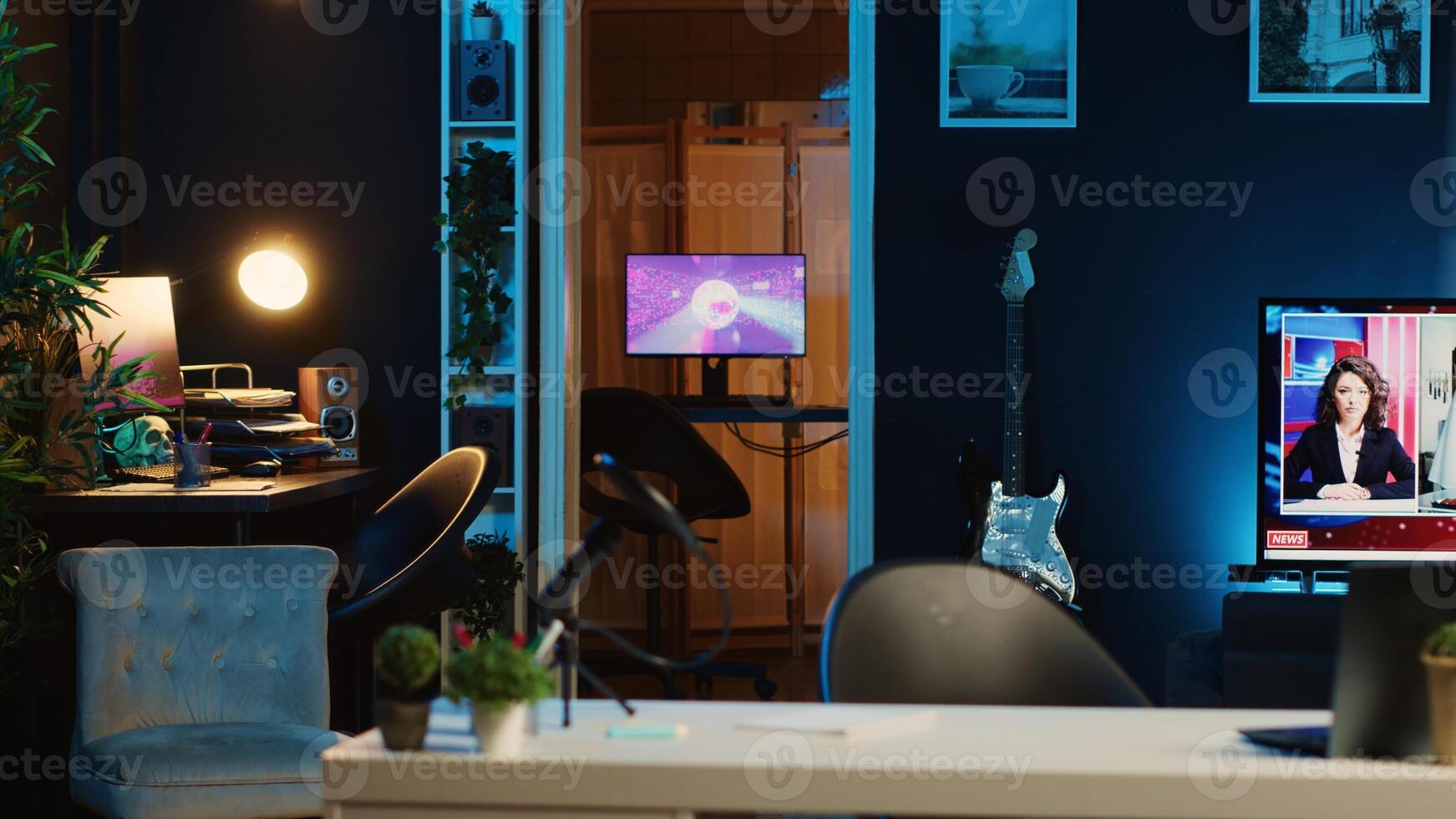 Computer screens showing abstract animation rendering in dimly lit empty home interior. 3D renders on digital displays in neon illuminated cozy apartment living room with TV running in background photo