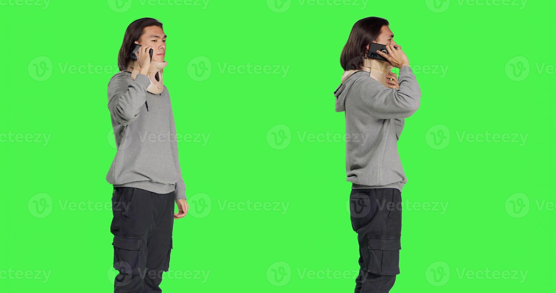 Young man having neck brace makes phone call informing people about his vertebral fracture accident. Greenscreen of wounded person wearing cervical foam collar, speaking on telephone. photo