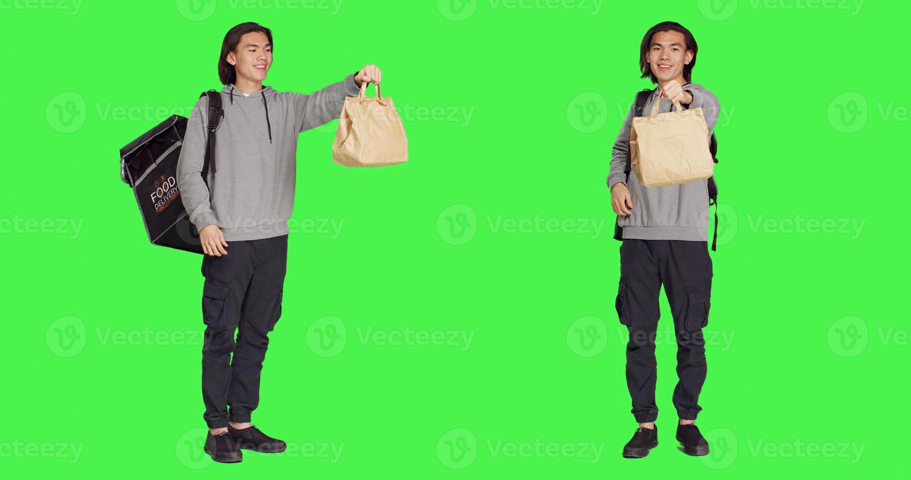 Standing over full body greenscreen, asian guy operates on food delivery with heated backpack. Young man holding bag for takeaway, prepared to give meal orders to customers. photo