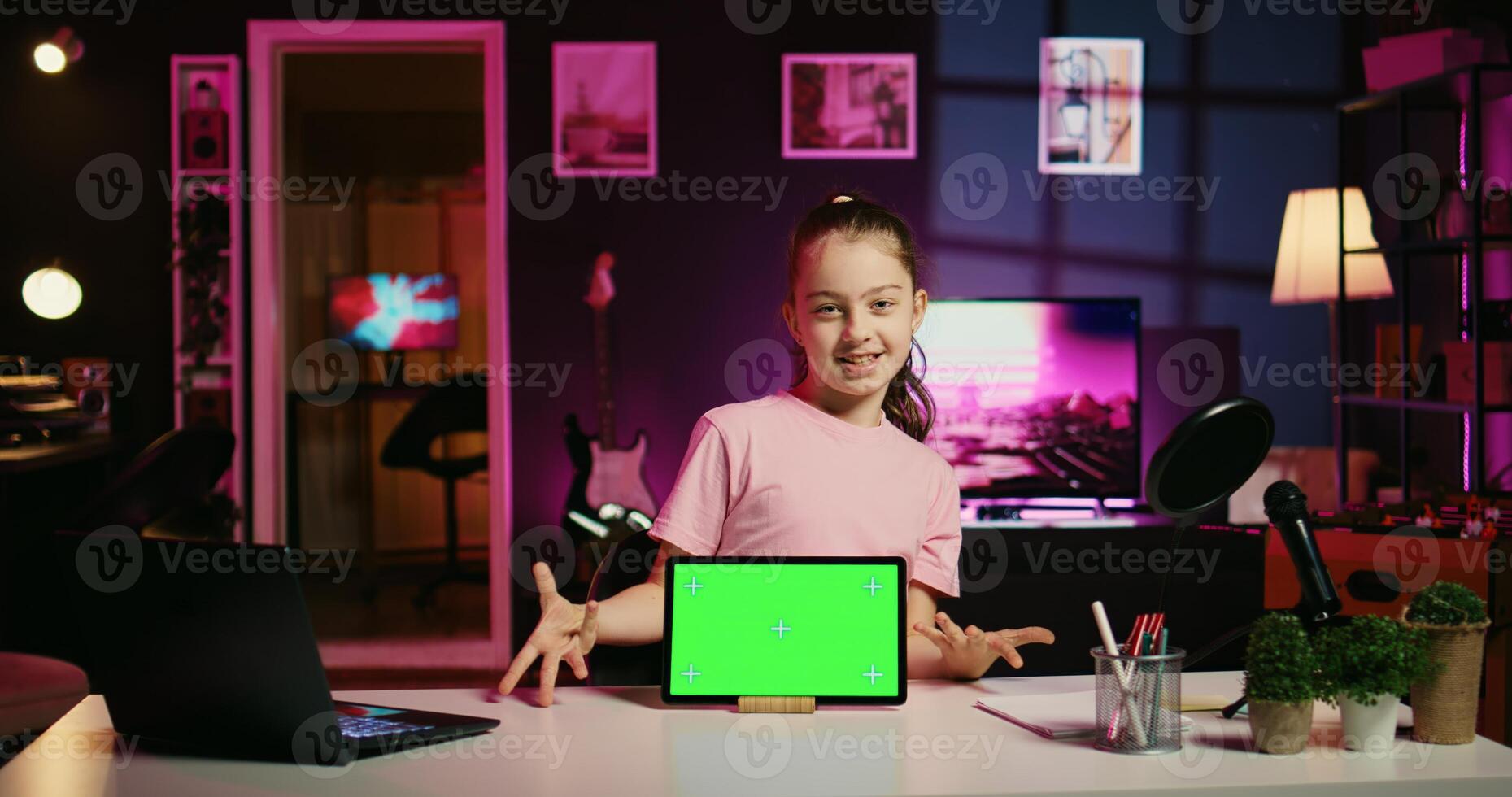 Smiling daughter filming online content with her parent using green screen tablet from sponsoring brand. Happy kid and her mother do internet videos for fans using chroma key device photo