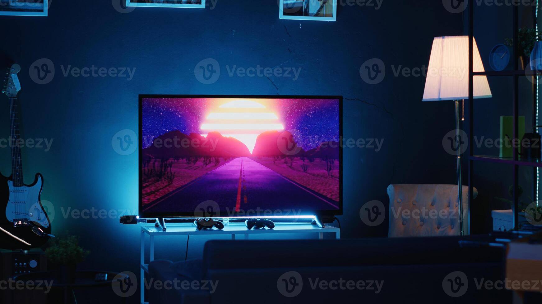 Empty stylish neon lit home studio interior illuminated with neon lights at night and artwork decorating the walls. Modern apartment with TV running in background on news channel broadcast photo