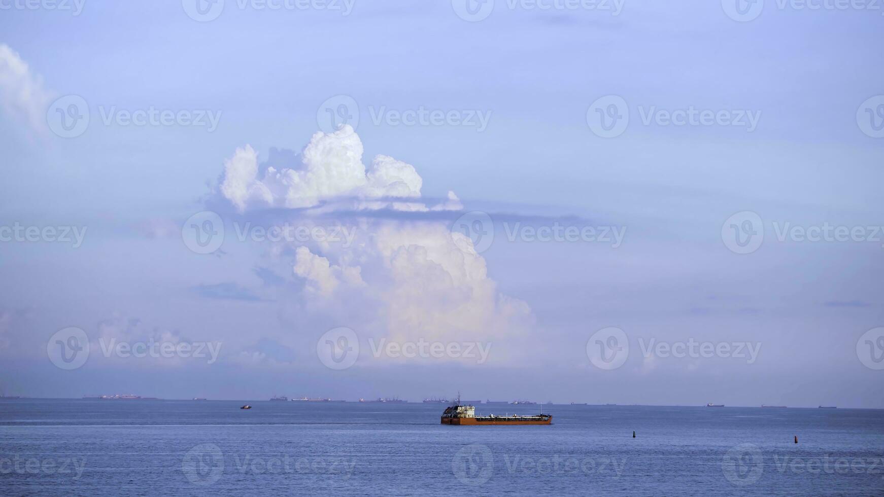 Breathtaking seascpe with a sailing red barge on blue cloudy sky on the background, water transport concept. Shot. Cargo ship barge on the sea horizon in a summer sunny day. photo