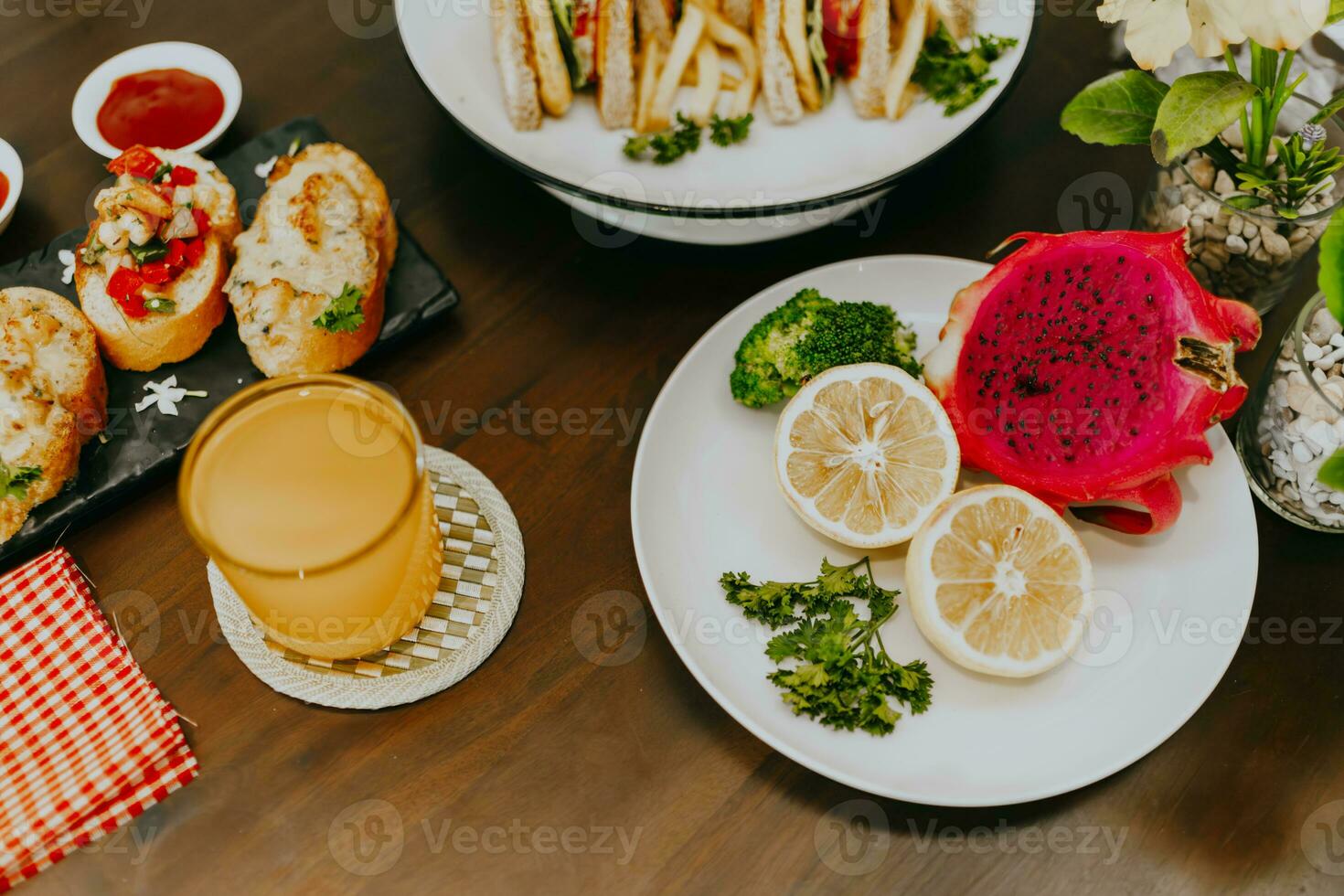 Appetizer table with Italian antipasti snacks and orange juice in glasses. Fresh lemon and dragon fruit on white plate. Brushetta or authentic traditional Spanish tapas set over wooden table. photo