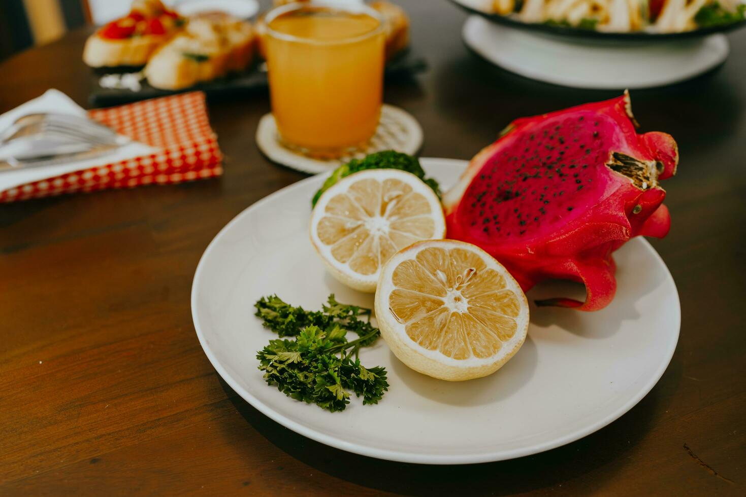 Appetizer table with Italian antipasti snacks and orange juice in glasses. Fresh lemon and dragon fruit on white plate. Brushetta or authentic traditional Spanish tapas set over wooden table. photo