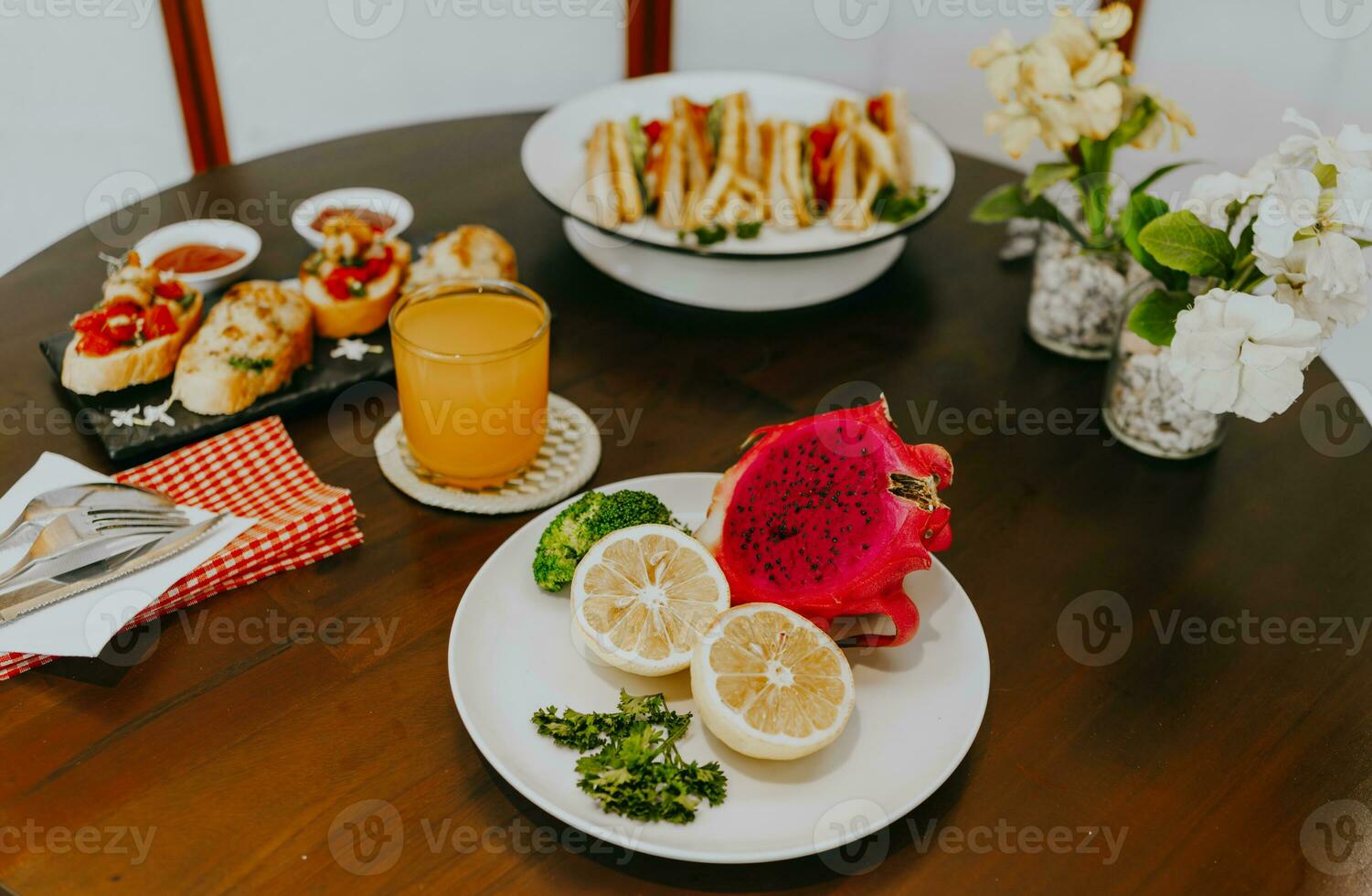 Appetizer table with Italian antipasti snacks and orange juice in glasses. Fresh lemon and dragon fruit on white plate. Brushetta or authentic traditional Spanish tapas set over wooden table. photo