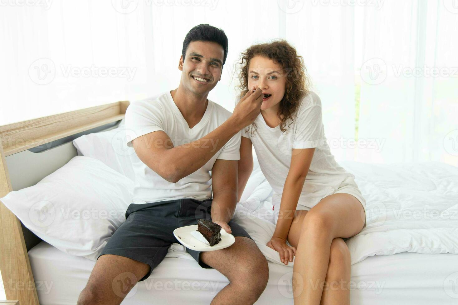 Smiling and happy couple having dessert in bed in the morning photo