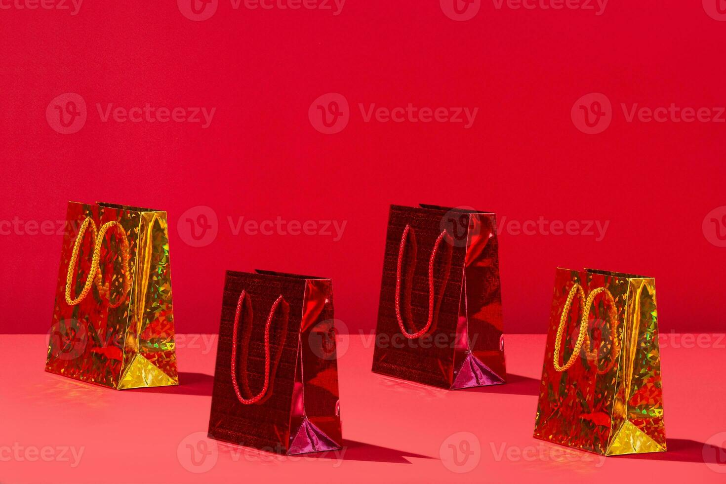 Yellow and red bright gift paper shopping bags on red background. Copy space for text shadow photo
