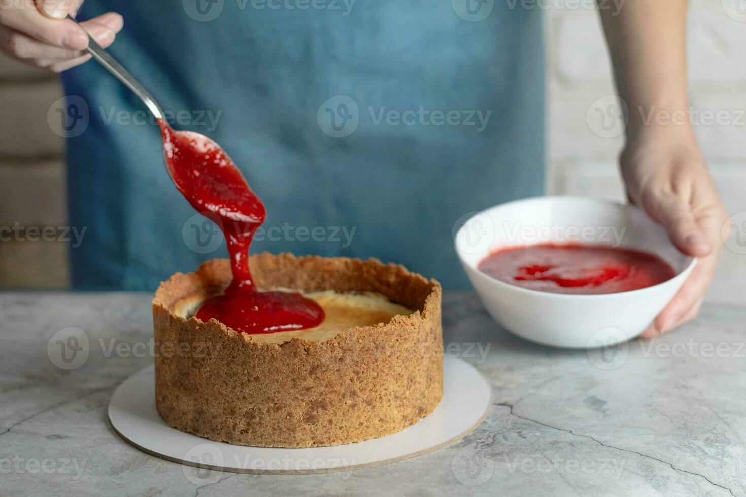 Woman making cheesecake, spoons out strawberry confiture, close up photo food