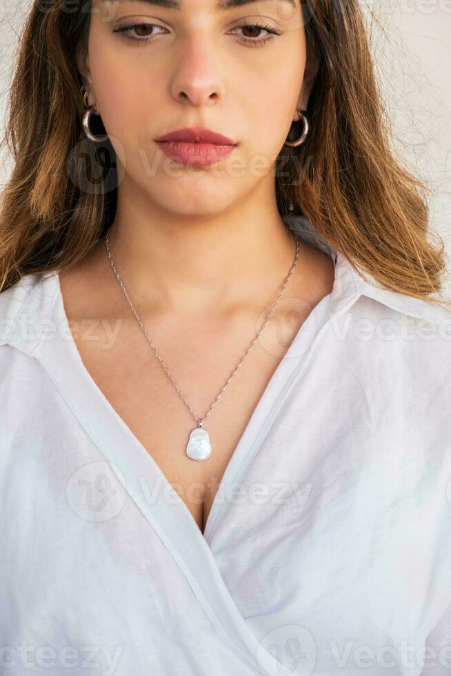 joven mujer vistiendo un plata cadena perla collar y plata pendientes. foto