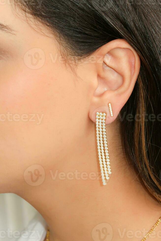 Woman wearing beautiful tennis chain earrings with zirconia. photo