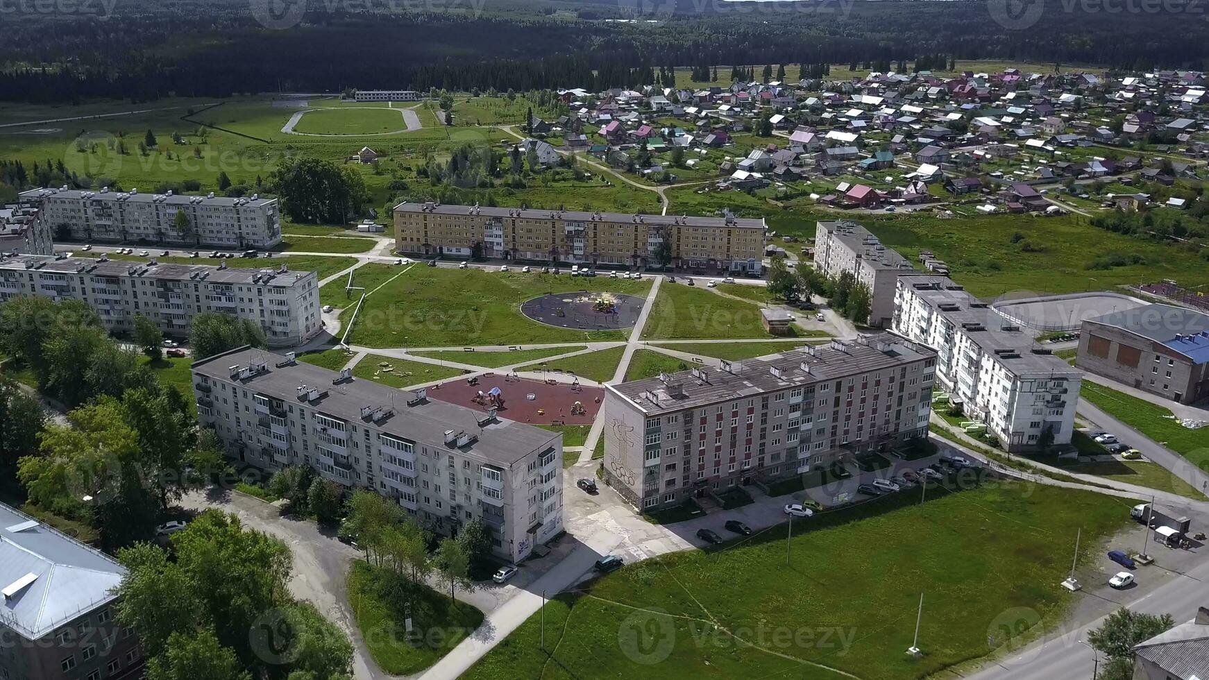 View from the height of the helicopter . Clip. Small houses next to large trees and parks , as well as a road on which a few cars drive photo