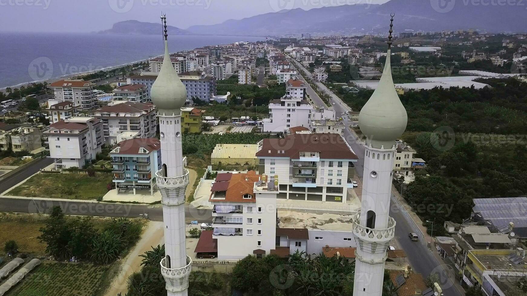 Beautiful view of the city. Clip. A mosque with domes next to houses and in the background the sea and mountains and green forests. photo