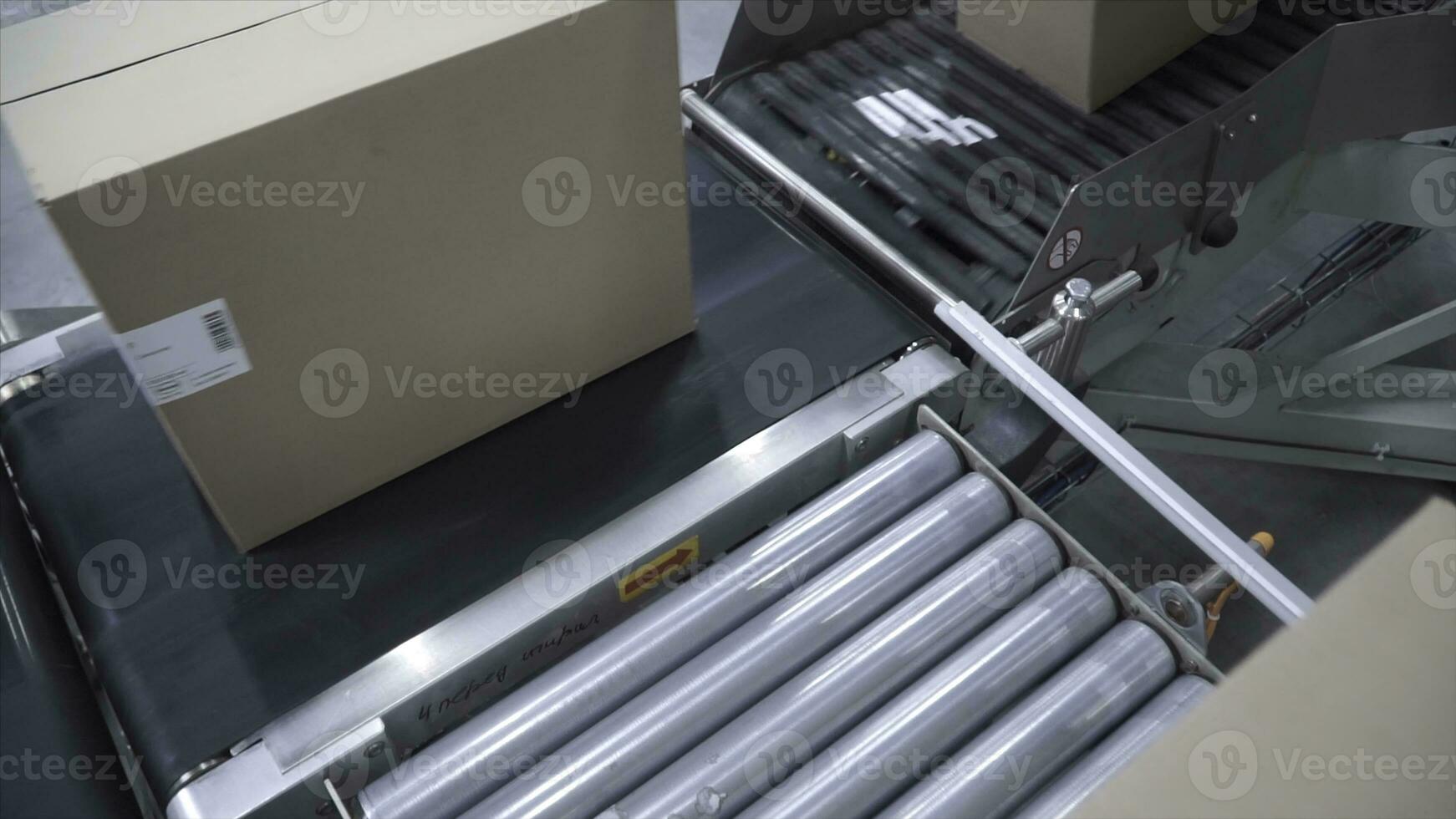 Cardboard boxes on conveyor belt in factory. Clip. Cardboard boxes on conveyor belt in distribution warehouse. Packed courier on production line against grey background photo