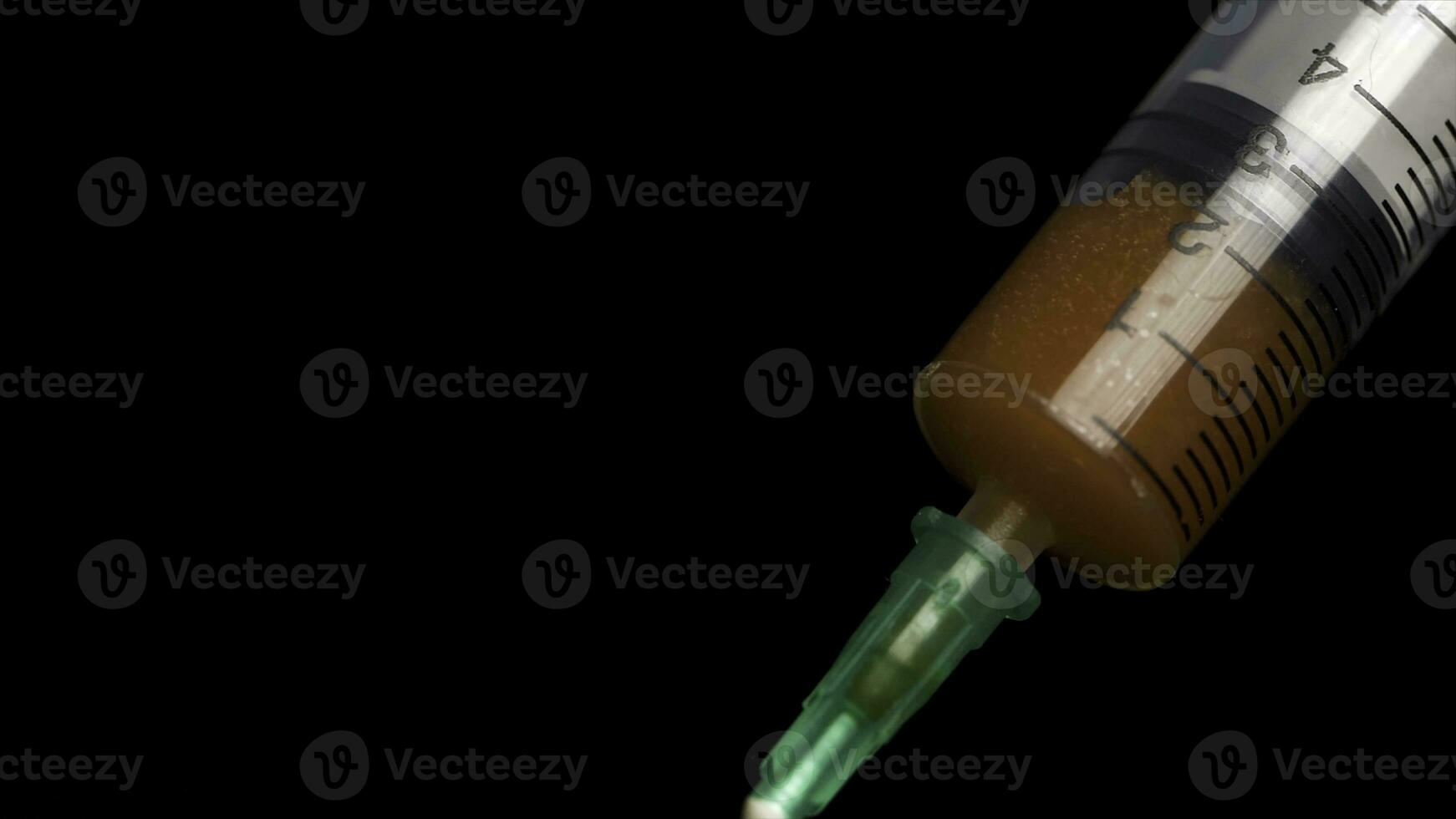 Close-up of a drop of blood on a syringe. In a blurred black background lies a test tube with blood. Close up syringe with red solution syrup. Medical Concept. Preparing medicine Procedure. photo