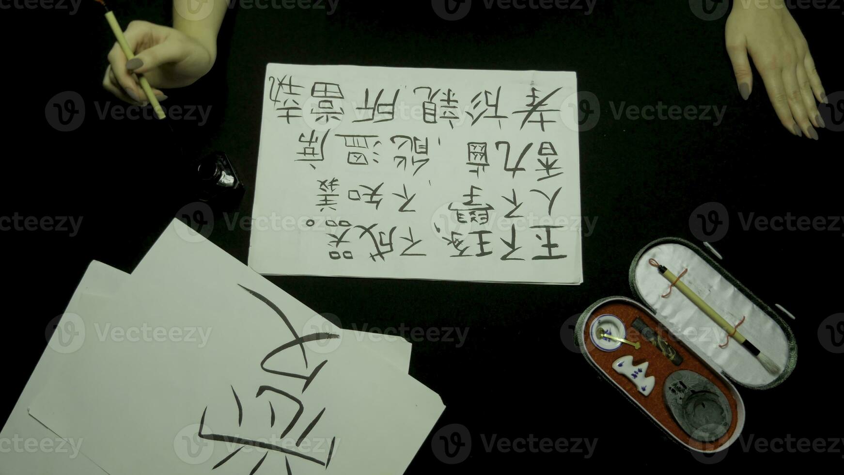 Female hand writing chinese calligraphy using brush and ink on rice paper. Close up on hand holding brush while writing calligraphy. chinese painting and calligraphy photo