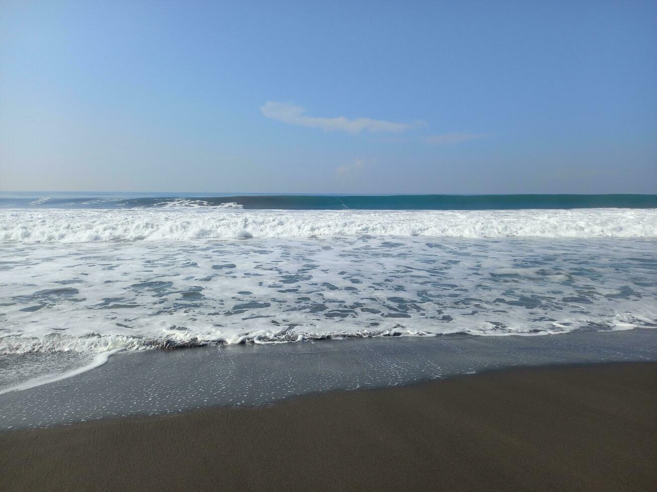 Tropical beach with waves and blue sky. Daylight shore scenery. Coast panoramic view photo