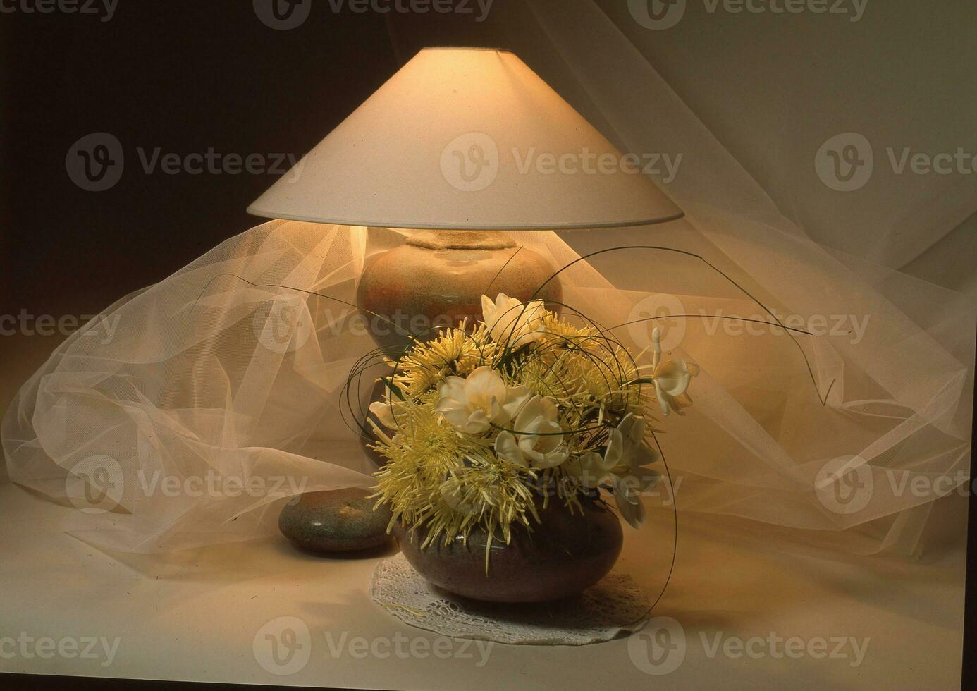 a vase with flowers and a lamp on a table photo