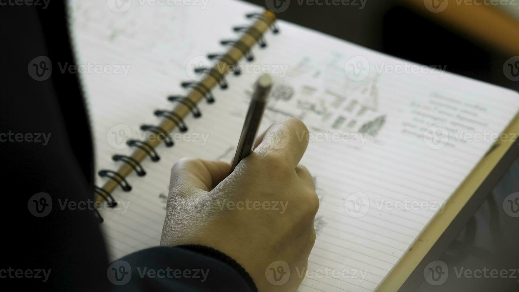 Hands holding pencil to write or to draw in a notebook. Adult colouring with soft tip pencils. Female hand drawing pencil in the notebook close-up photo