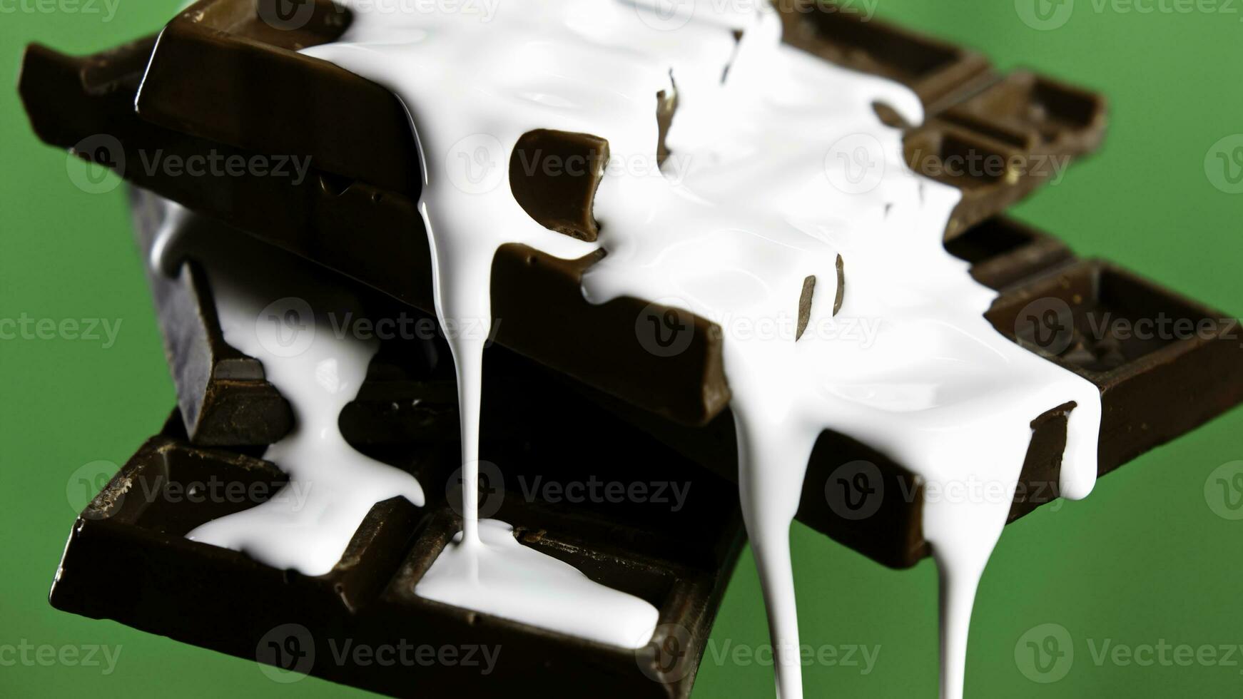 Close up of chocolate bars with draining white glaze isolated on chroma key green wall background. Stock clip. Black chocolate and white glaze. photo