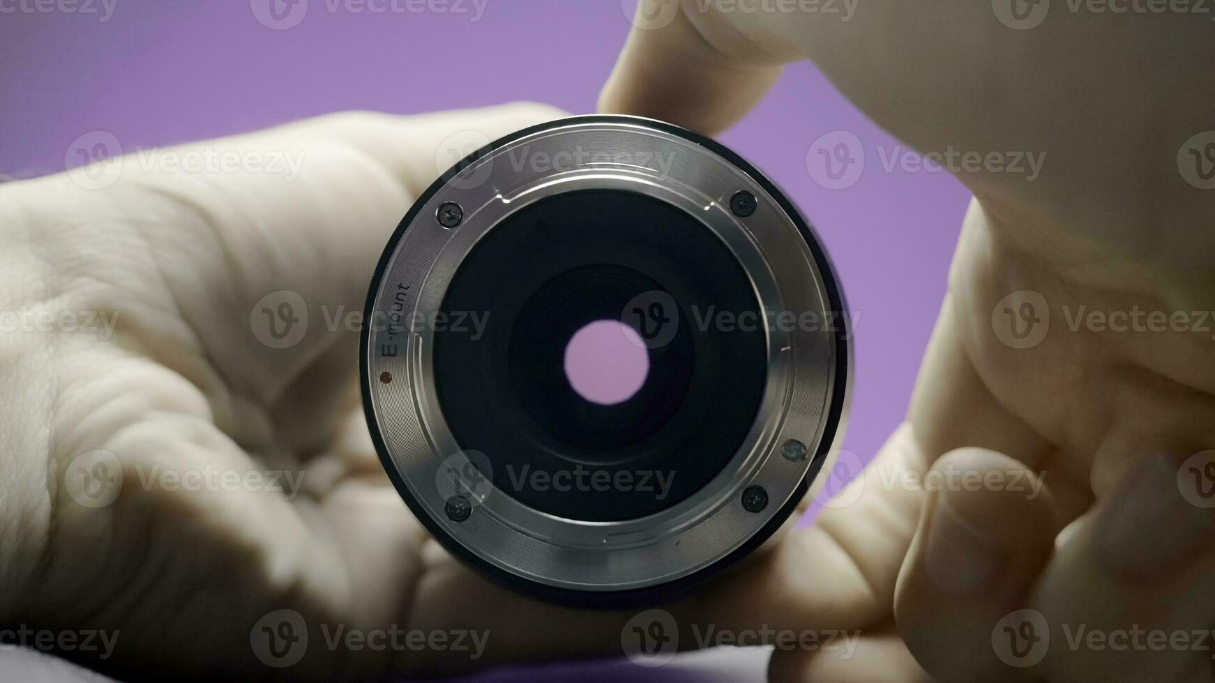 Close-up of man rotating lens. Action. Photographer turns ring of professional lens on isolated background. Lens of lens changes size from rotation of ring by photographer photo