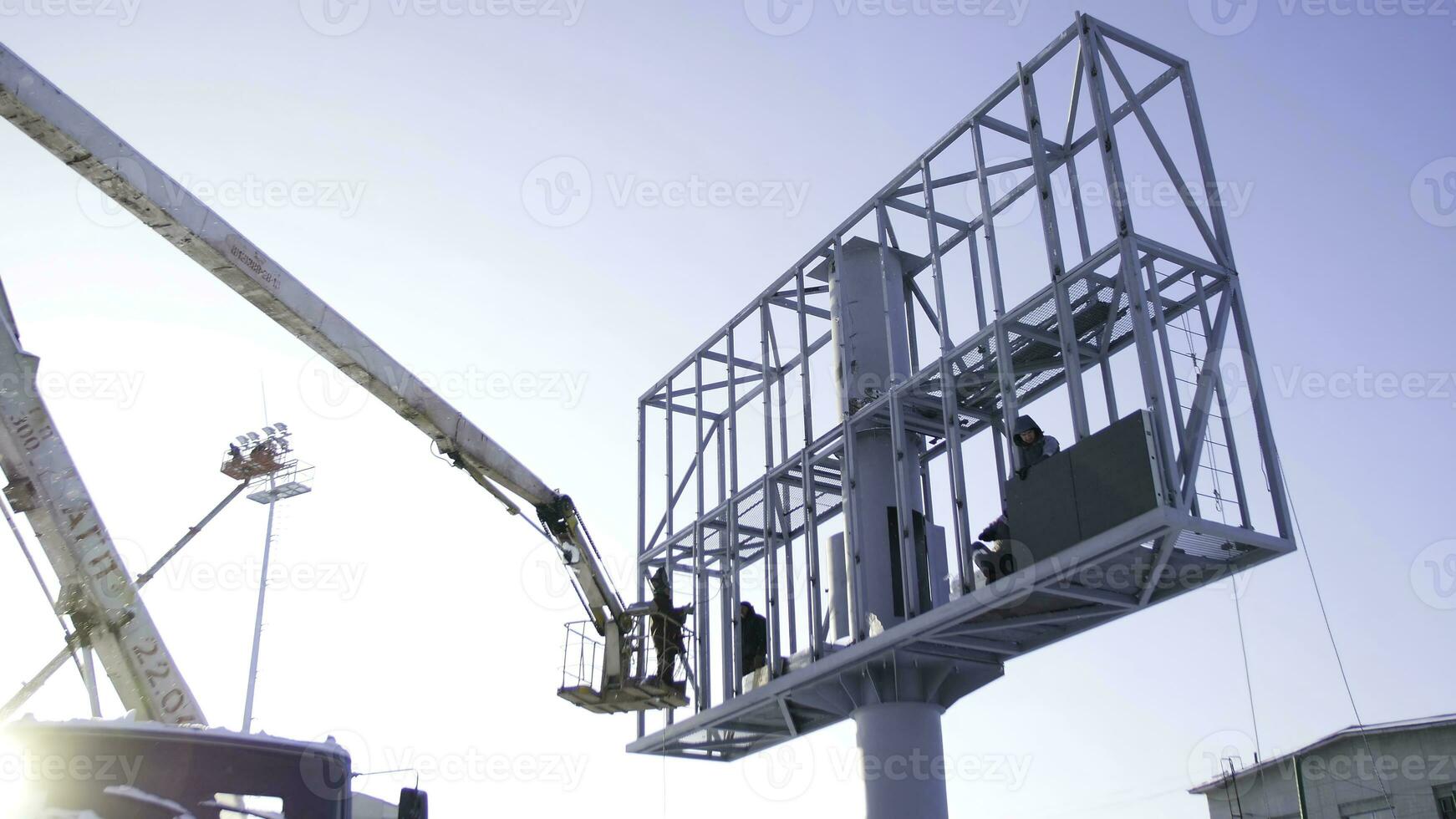 Builder on a Lift Platform at a construction site. Men at work. construction worker assembling scaffold on building site. Men assemble Billboard on tap photo