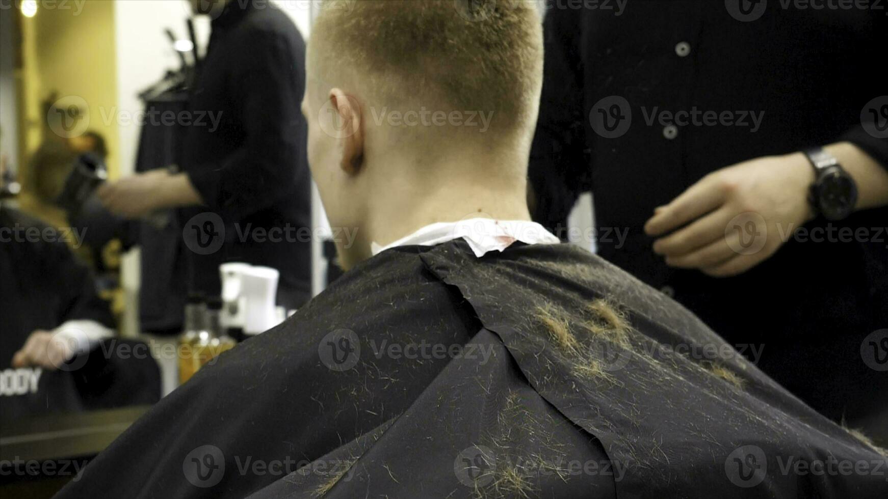 Barber cutting hair with scissors and hair flying in the air in slow motion. Back view of man in barber shop and flying hair in slow motion. Close-up back view of young bearded man getting beard photo