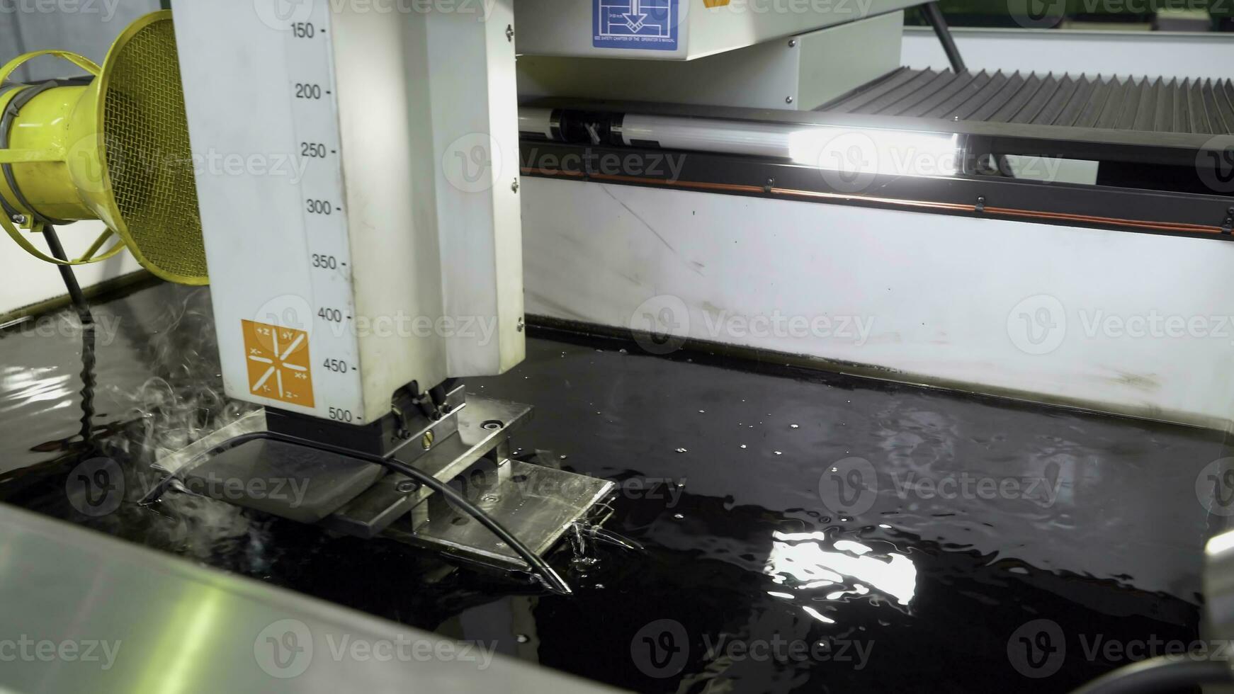 Metal cutting under water at factory. Scene. Processing of steel part that is cooled by water and fan unit at enterprise. Underwater metal cutting method photo