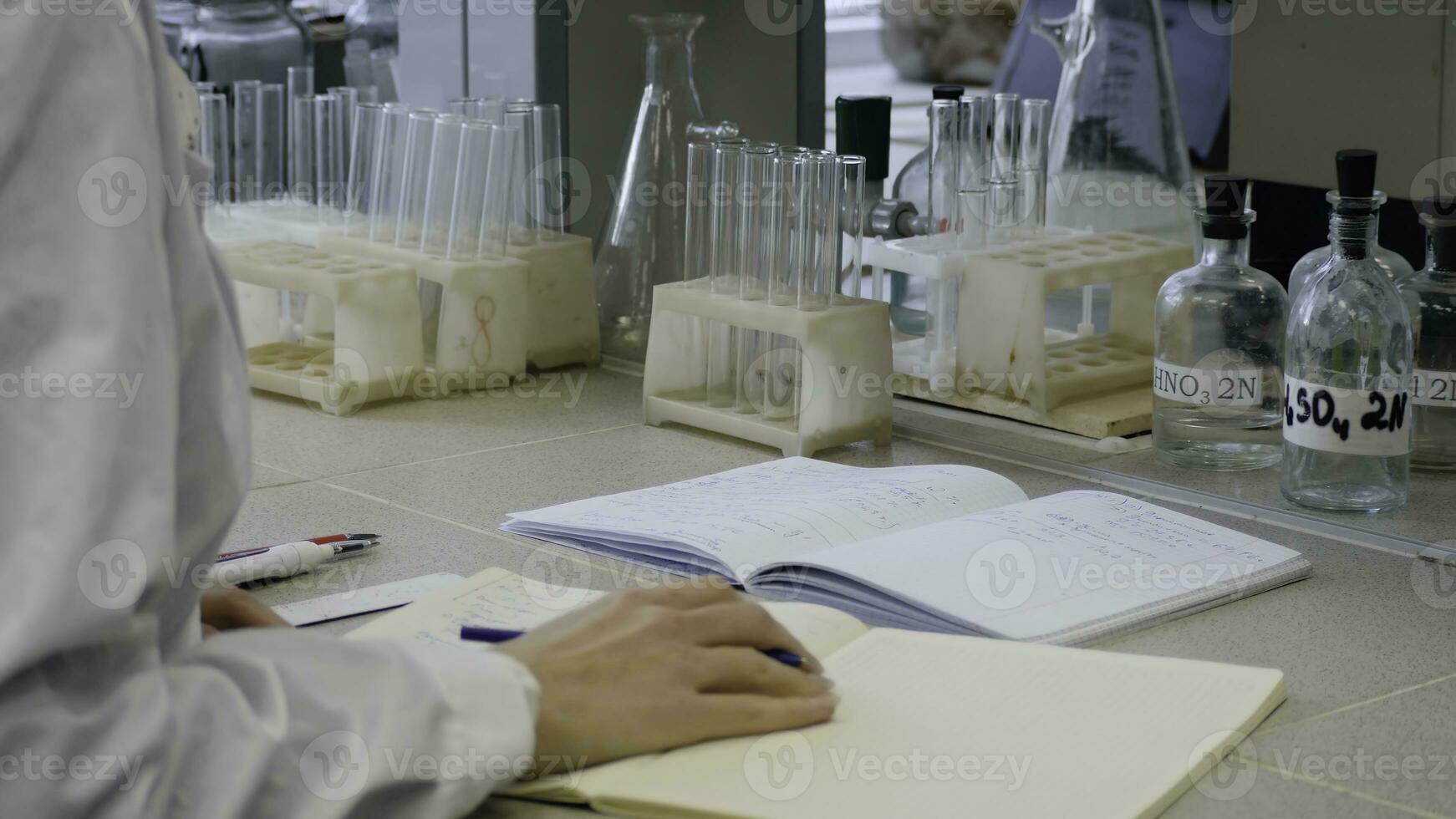 Young scientist doctor taking notes. Female scientist takes notes in the background are the tubes photo