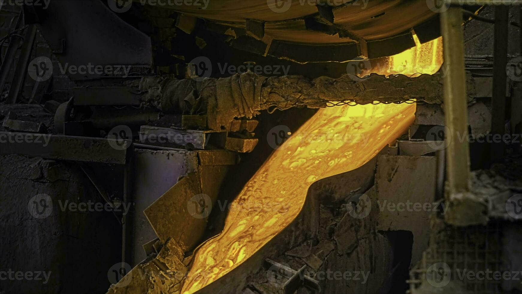 Close-up of molten metal flowing in factory. Stock footage. Beautiful molten substance flows down drain at steel plant. Melting operations and bright alloy flows photo