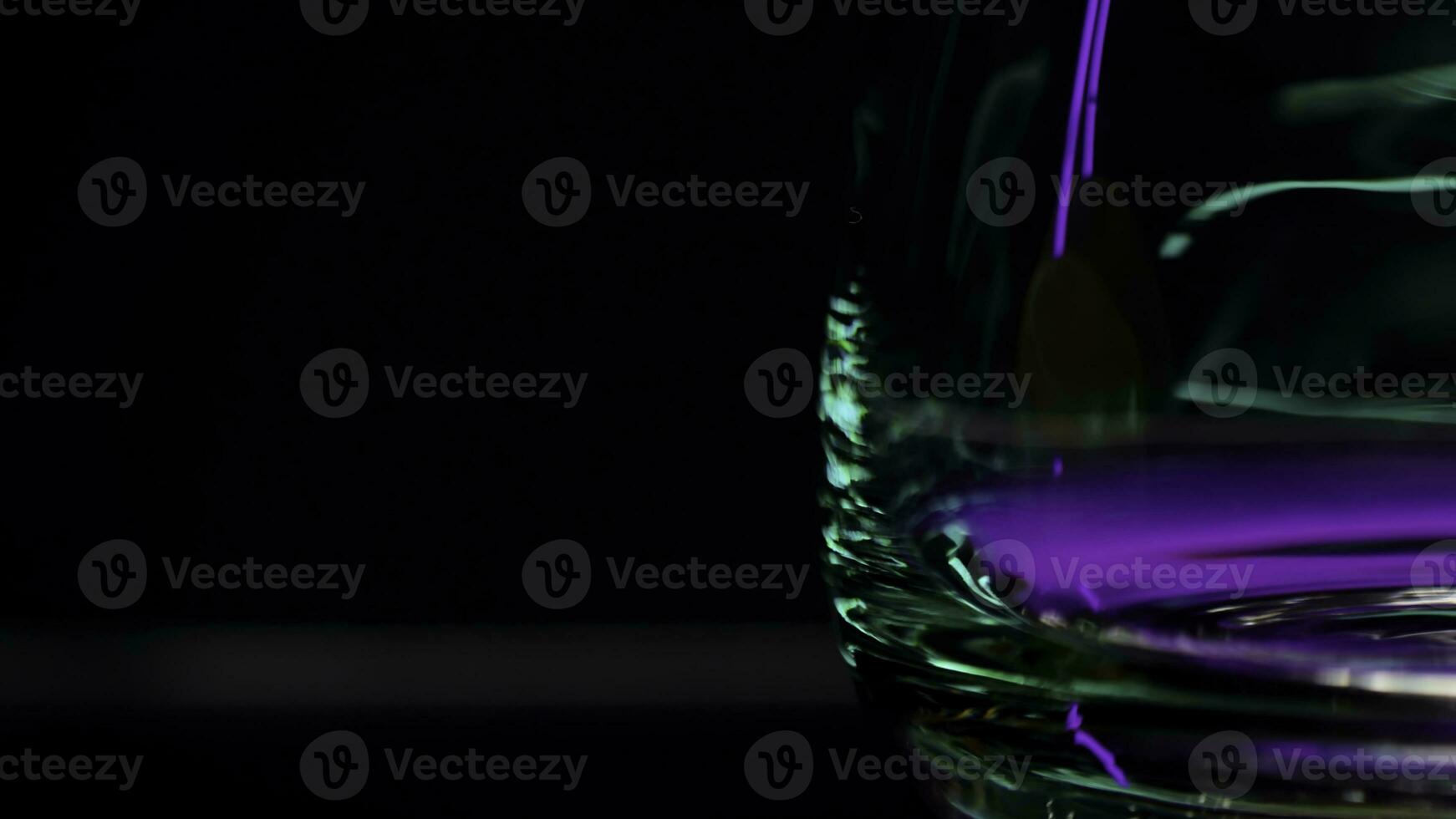Close up of empty transparent glass with the reflection of lights. Stock clip. Wall with colorful illumination of a night bar. photo