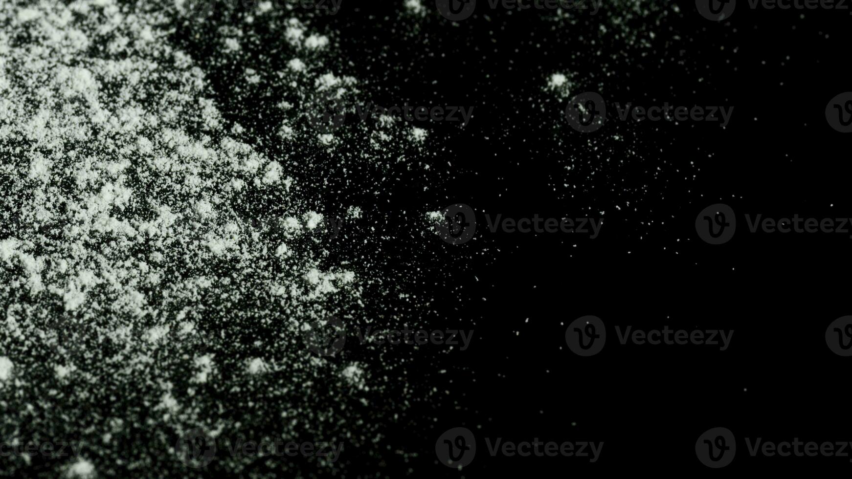 White powder falling down isolated on black background. Stock footage. White dry inks dropping on dark surface. photo