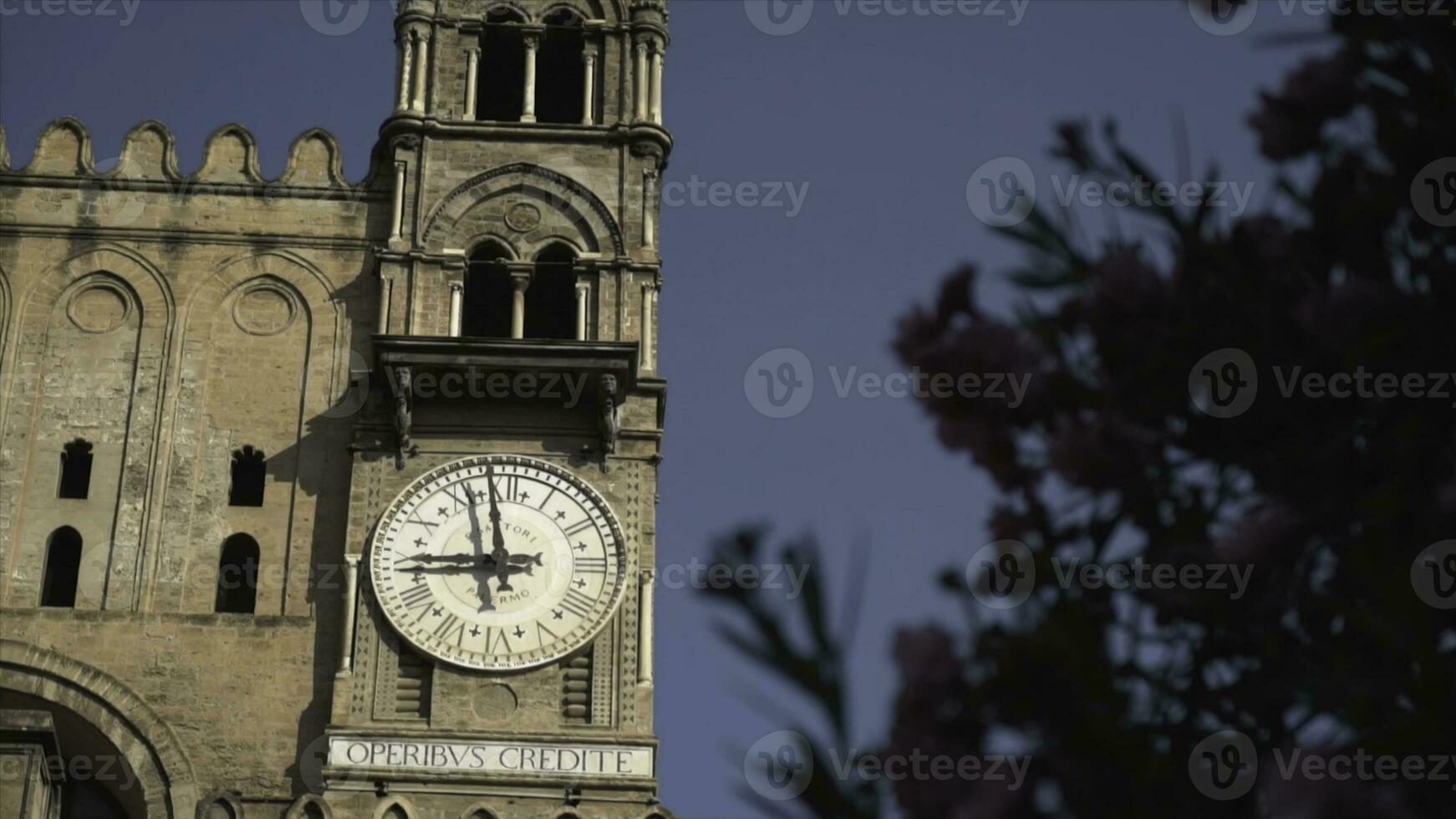 Bottom view of the old tower with clock on blue clear sky background. Action. Details of the ancient beautiful building with round old clock on brick tower, architecture concept. photo