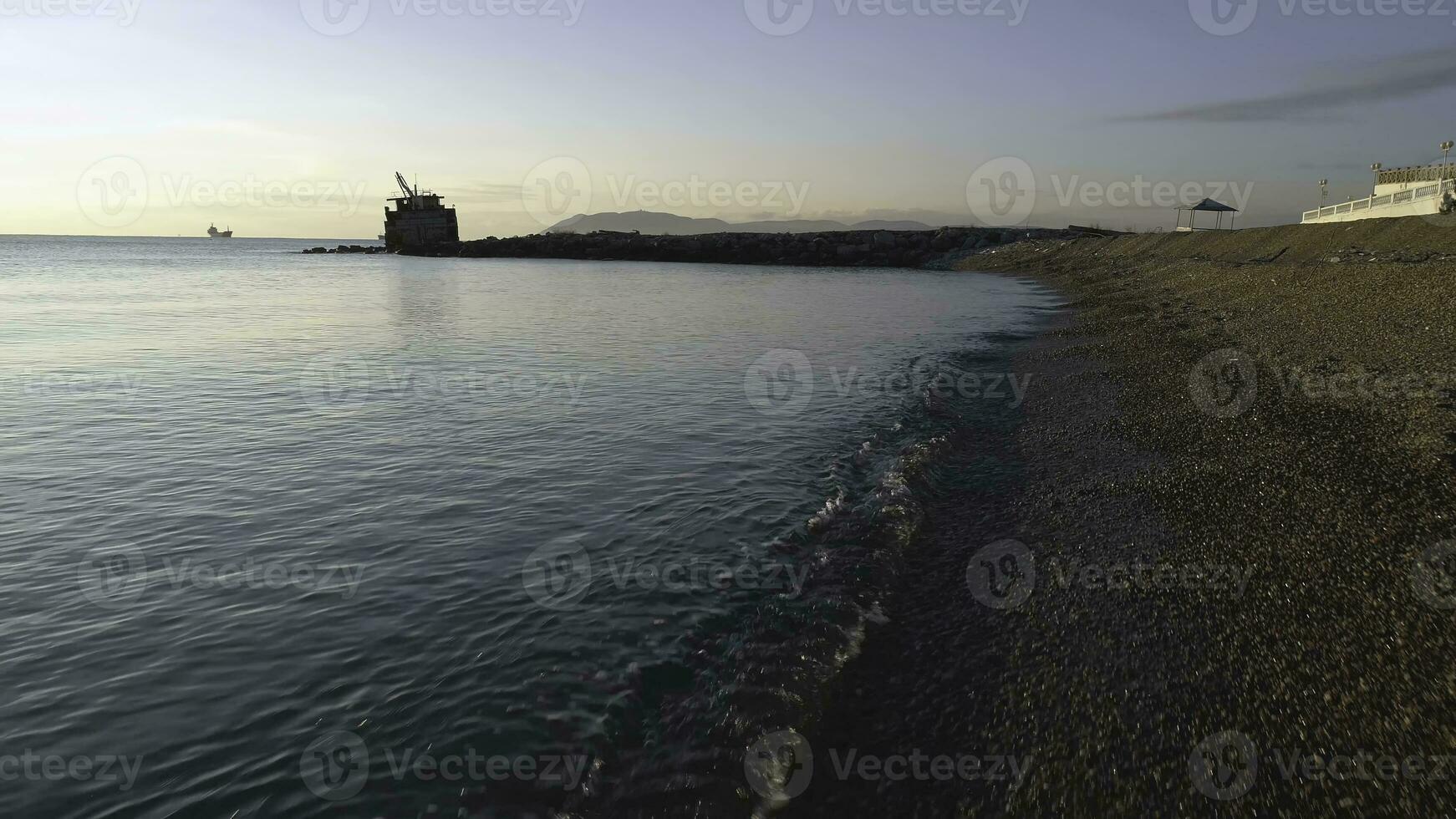 Stones on beach and sea water. Shot. Pebble beach at sunset. Beach scene with many pebbles in the dunes photo