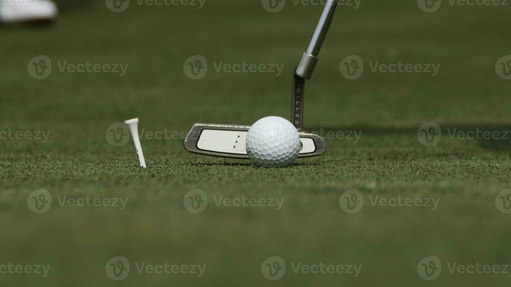 Professional golfer putting ball into the hole. Golf ball by the edge of hole with player in background on a sunny day photo