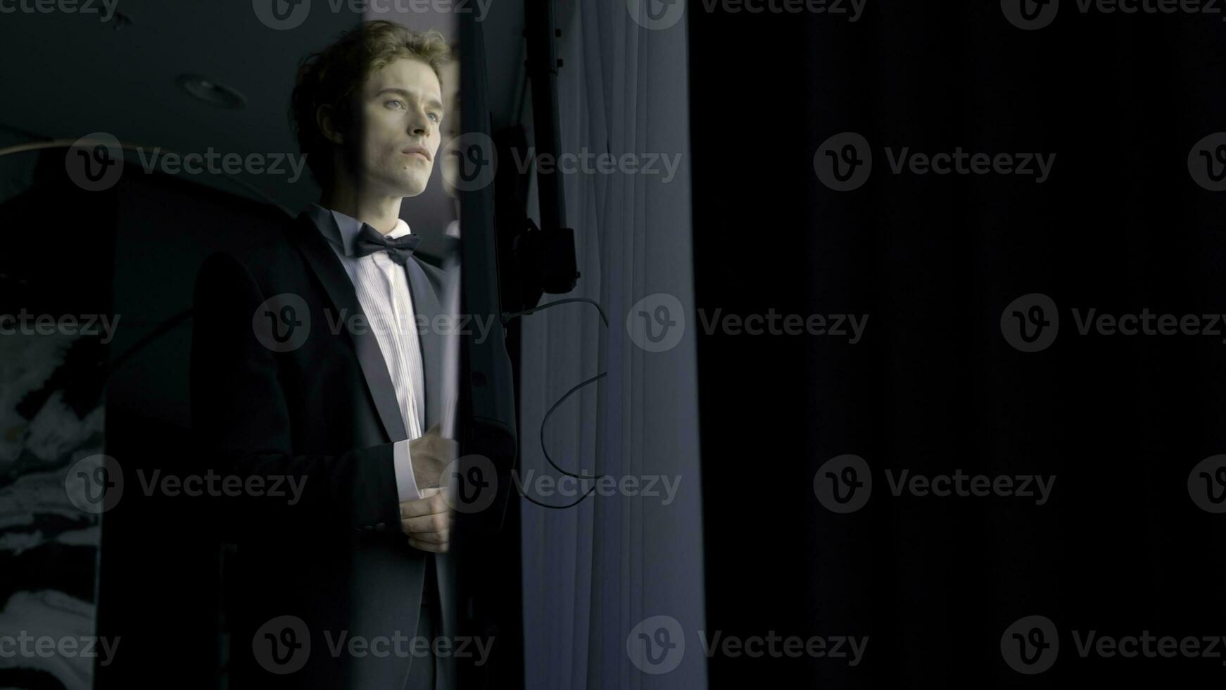 A worried groom man standing by the window. Action. Thoughtful attractive husband wearing suit before wedding ceremony. photo