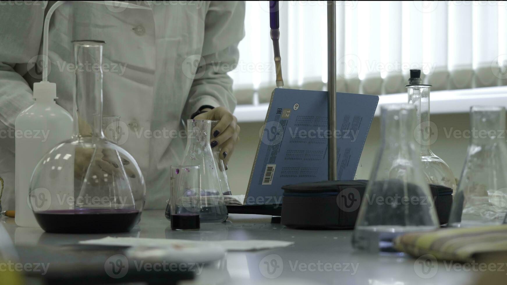 Lab technician doing experiment in lab. Male medical or scientific laboratory researcher performs tests with blue liquid. Scientist working with flasks in laboratory photo