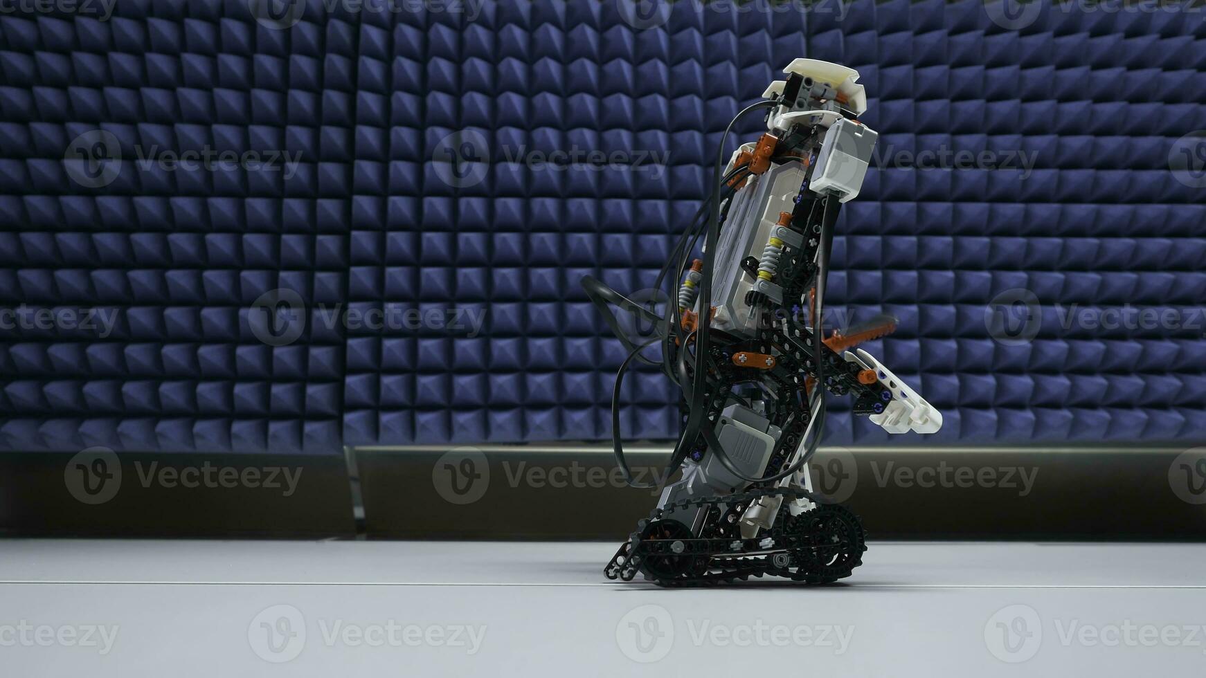 Small hunan-like robot sited on the table. Modern robot goes on the table close up photo