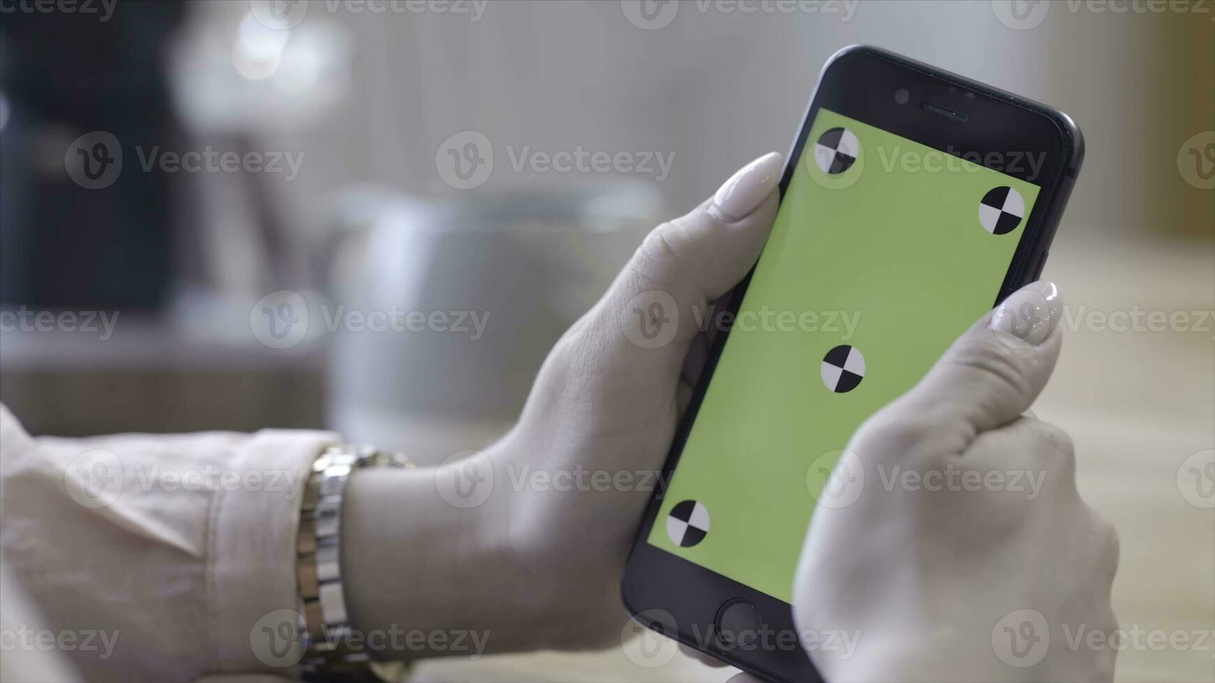 Young woman with beautiful manicure holding iPhone in hands and typing on the chroma key green screen. Stock footage. Technology, mockup and internet concept photo