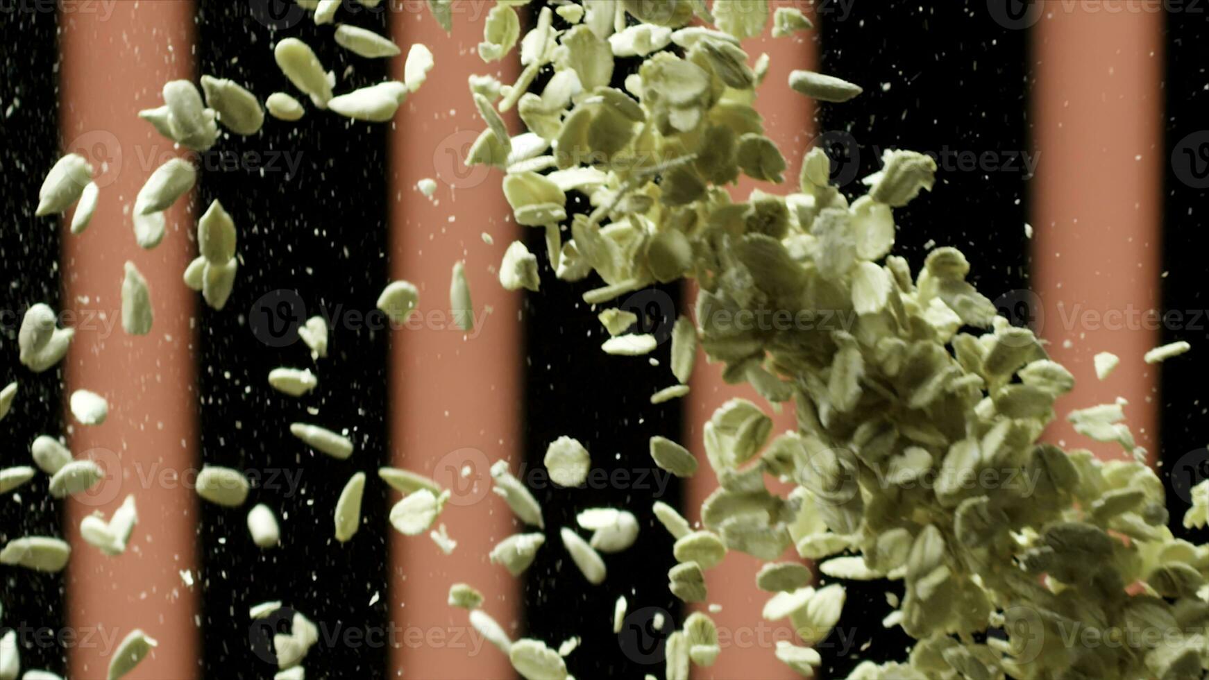 Close up of oat flakes falling down. Stock footage. Oatmeal splash, small flakes flying on black background with red vertical stripes, concept of healthy breakfast. photo