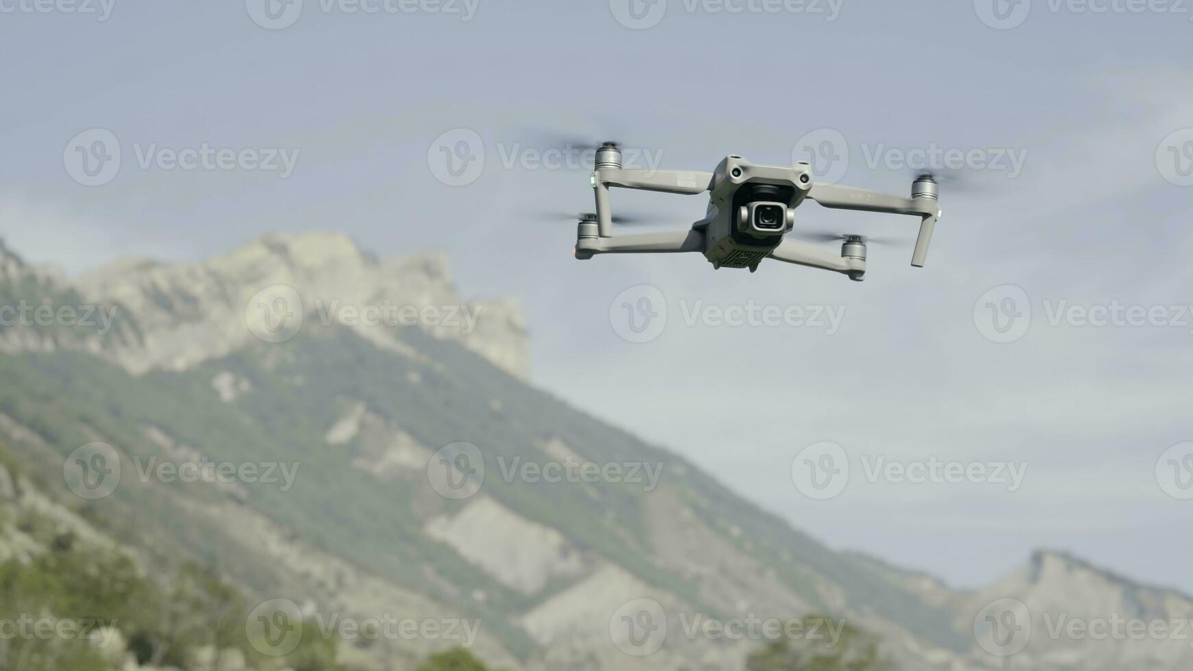 Aerial view of a quadcopter flying above green mountains on morning haze background. Action. Drone filming video of natural landscape. photo