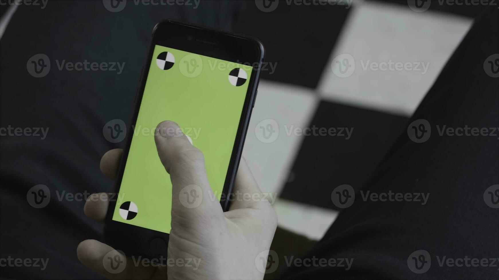 Man hands using mobile smartphone with green screen, over the shoulder view. Stock footage. Close up of man scrolling and tapping on Iphone screen with chroma key. photo