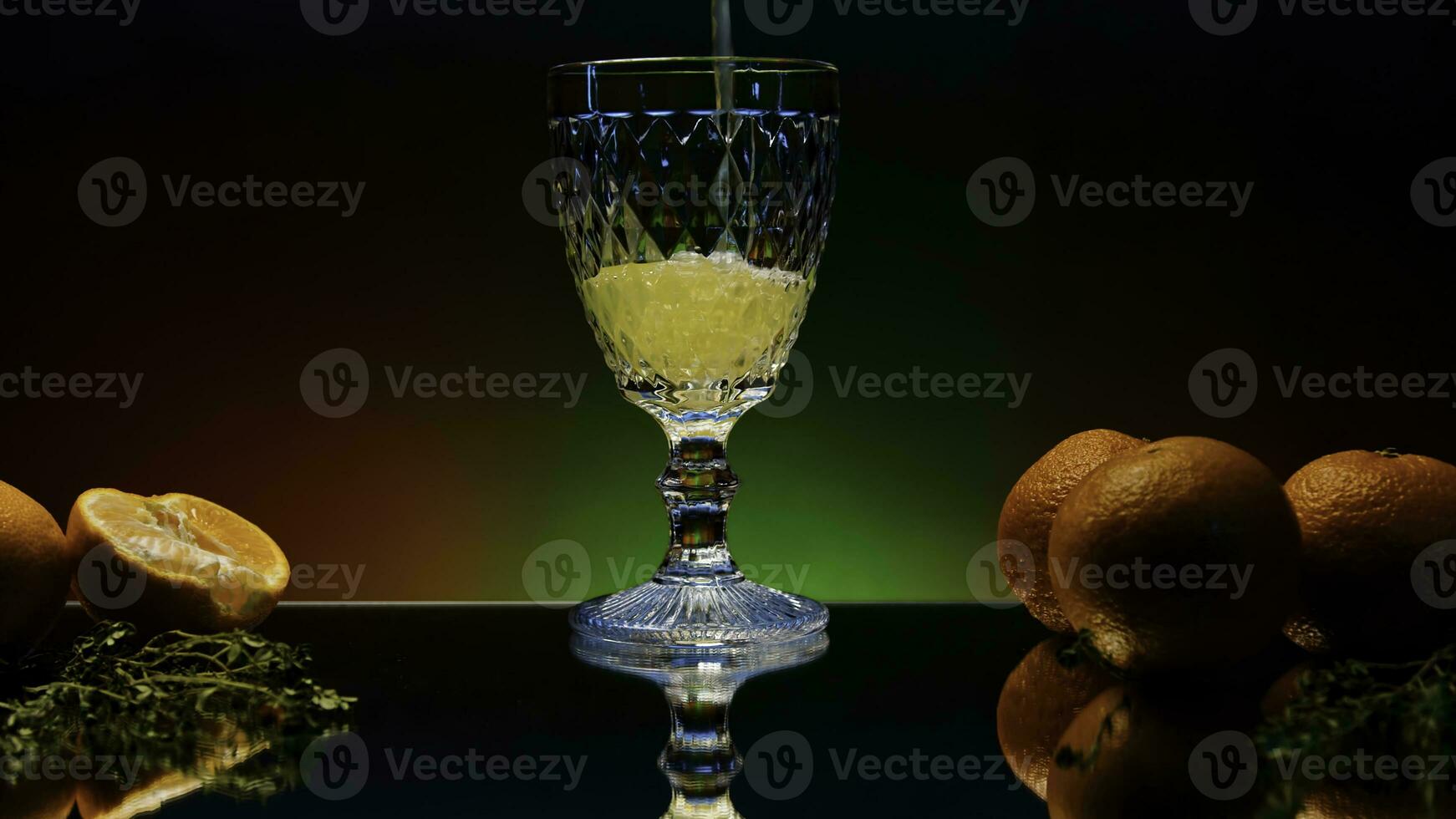 Close up of pouring orange soda into the glass. Stock clop. Soft drink with the taste of citrus and orange fruits on the reflective table surface. photo