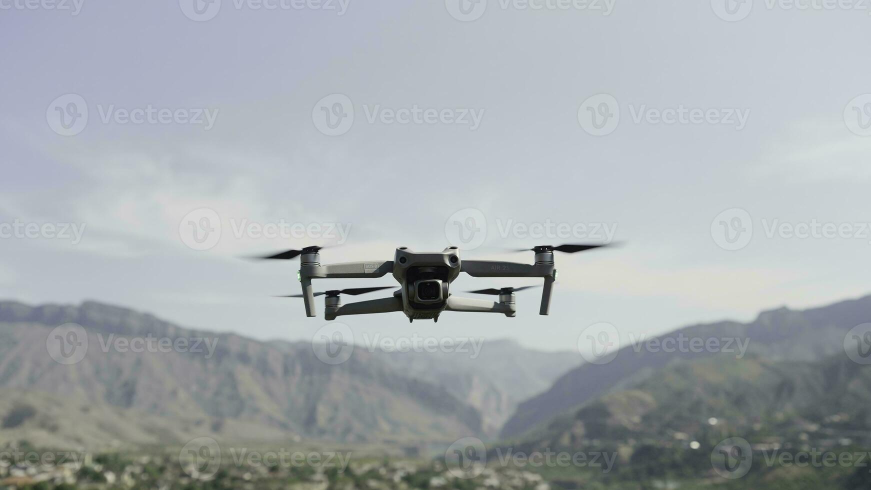 A drone flying over nature.Action. A small device for taking photos from a height in nature that shoots videos and spins in front of beautiful mountains in daylight.